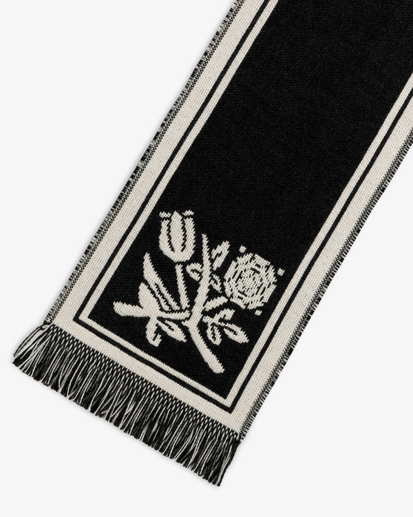 Wool Script Scarf in black with white border stripes, a floral design, and fringe at the ends.