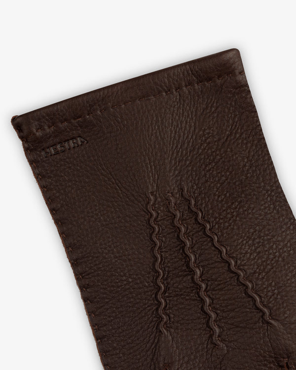 Close-up of brown leather Henry Gloves with three decorative stitched lines on the back.