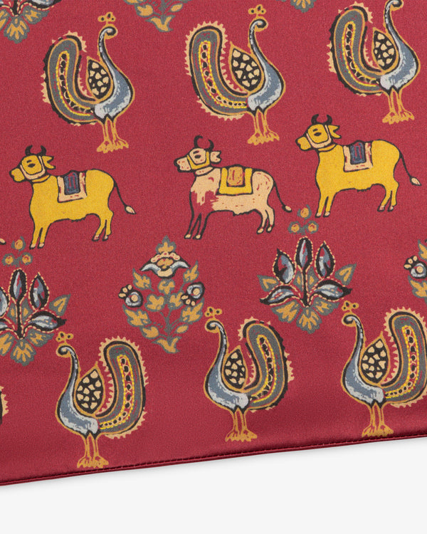 Archival Print Silk Fringe Scarf in red with repeating illustrations of roosters, cattle, and floral motifs.