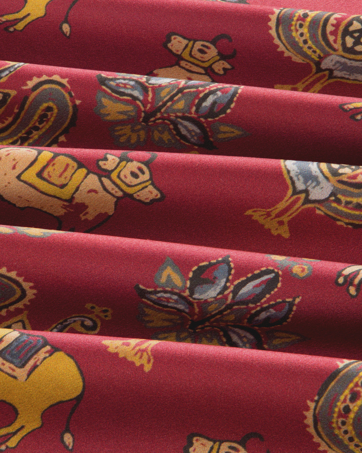 Archival Print Silk Tie Neck Blouse in red with a repeating pattern of stylized animals and floral motifs in yellow and blue.