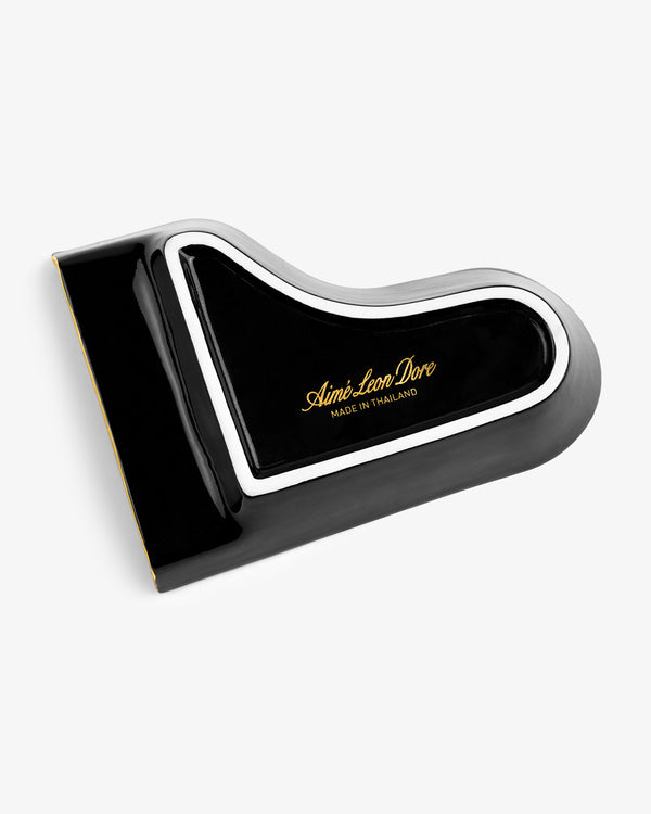Black Piano Ashtray shaped like a grand piano lid, with gold Aimé Leon Dore text and white trim on white background.