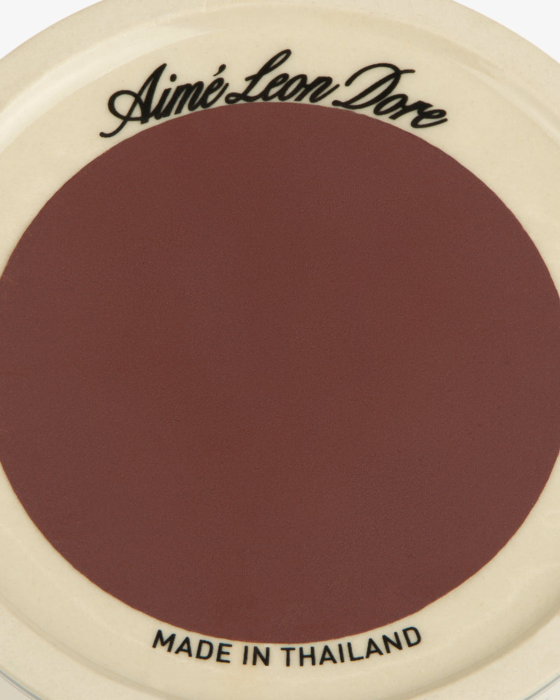 Porcelain Match Striker with Aimé Leon Dore text on top, Made in Thailand below. Brown center, cream border.