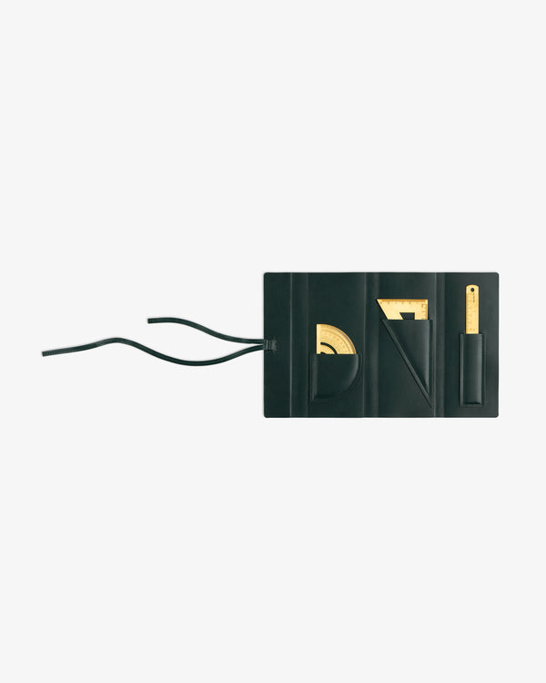 A black pouch with pockets holds the Brass Measurement Kit—protractor, set square, ruler, pencil—and two left strings.
