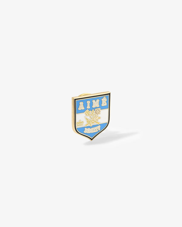 Shield-shaped Graphic Pin with AIMÉ & AMON, roses, blue, white & gold details on a white background.