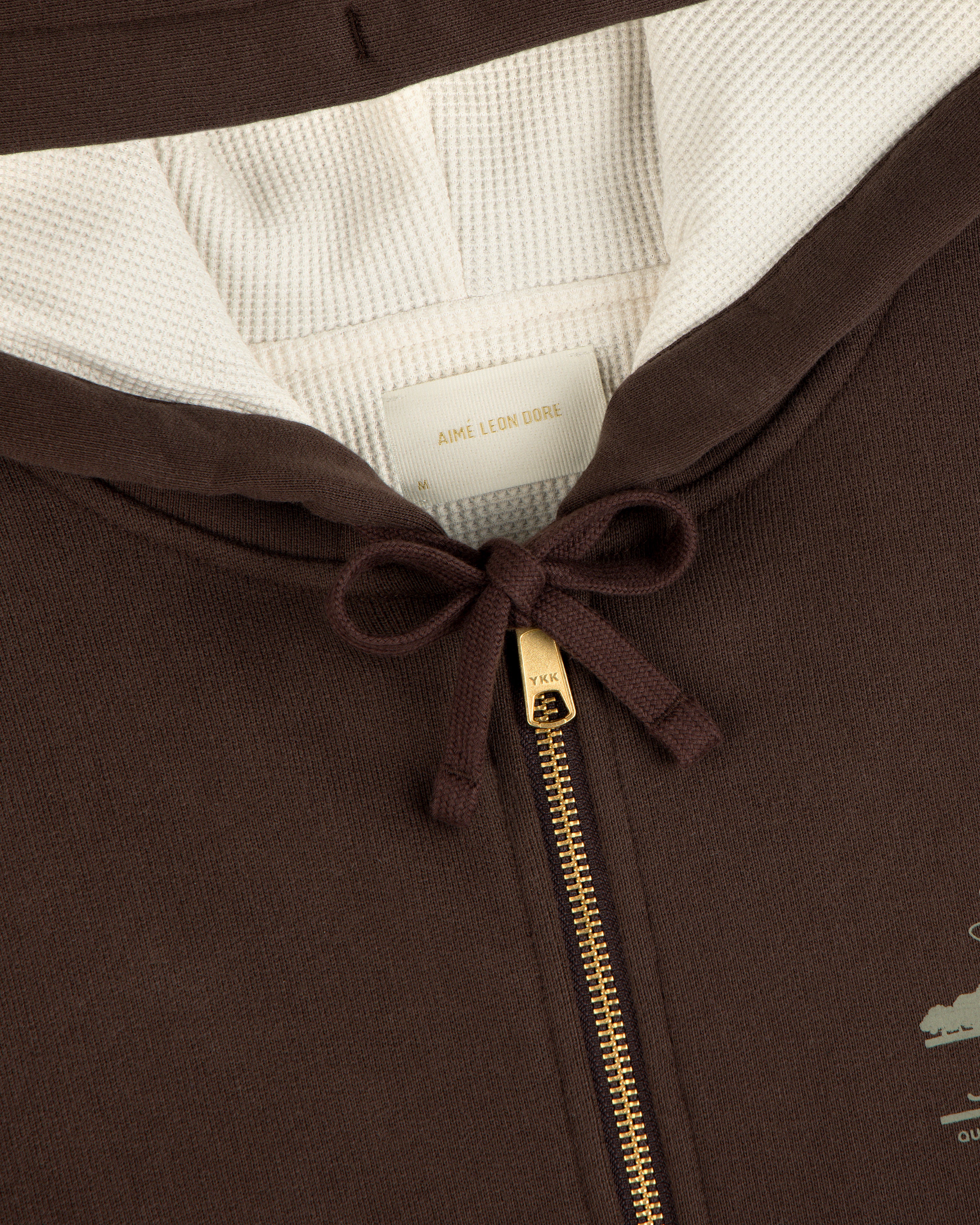 Close-up of the Unisphere Waffle Lined Full-Zip Hoodie with gold zipper, white lining, and collar tag visible.