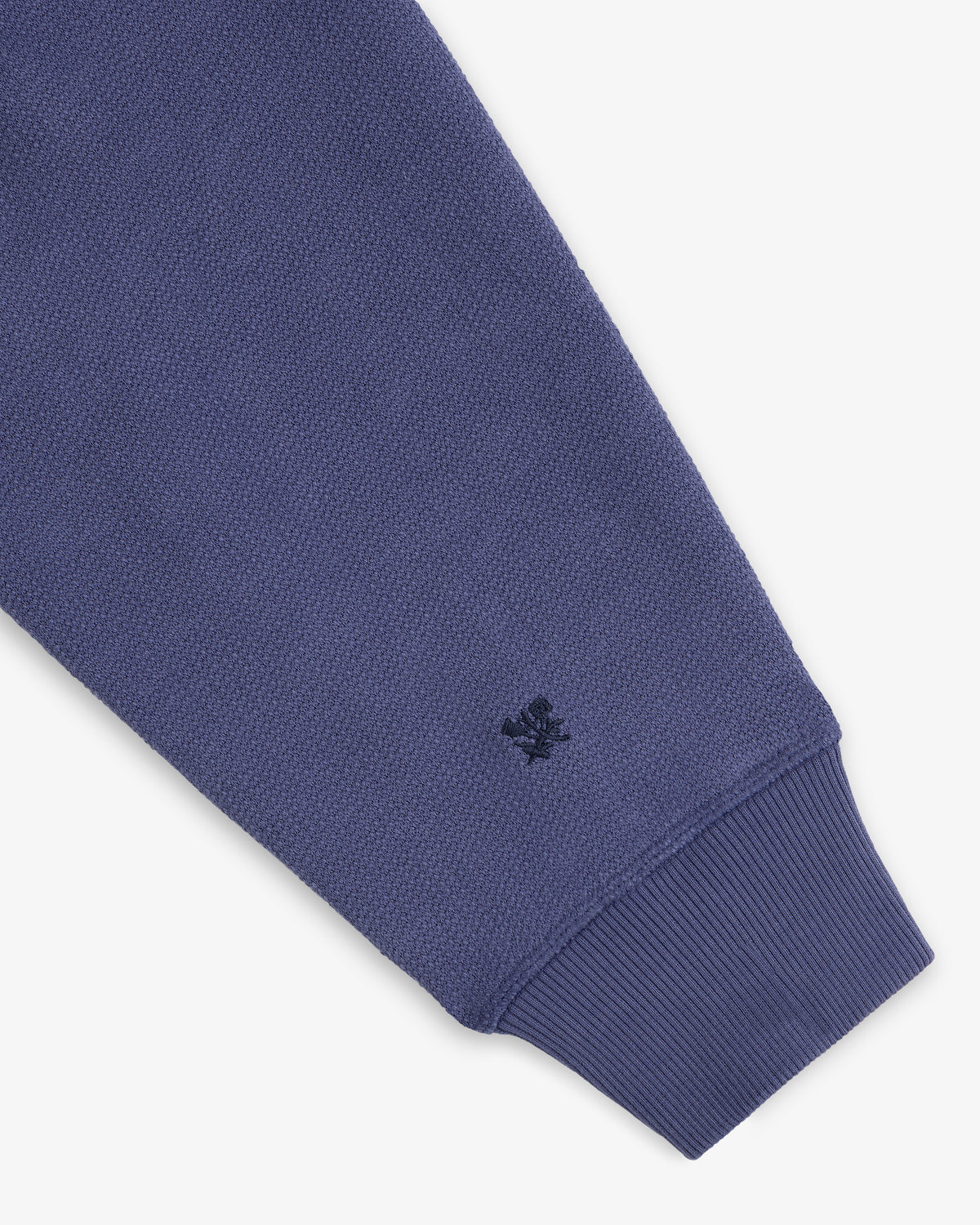 A close-up of the Stone Washed Marina Hoodie’s blue sleeve with ribbed cuff and a black logo near the wrist.
