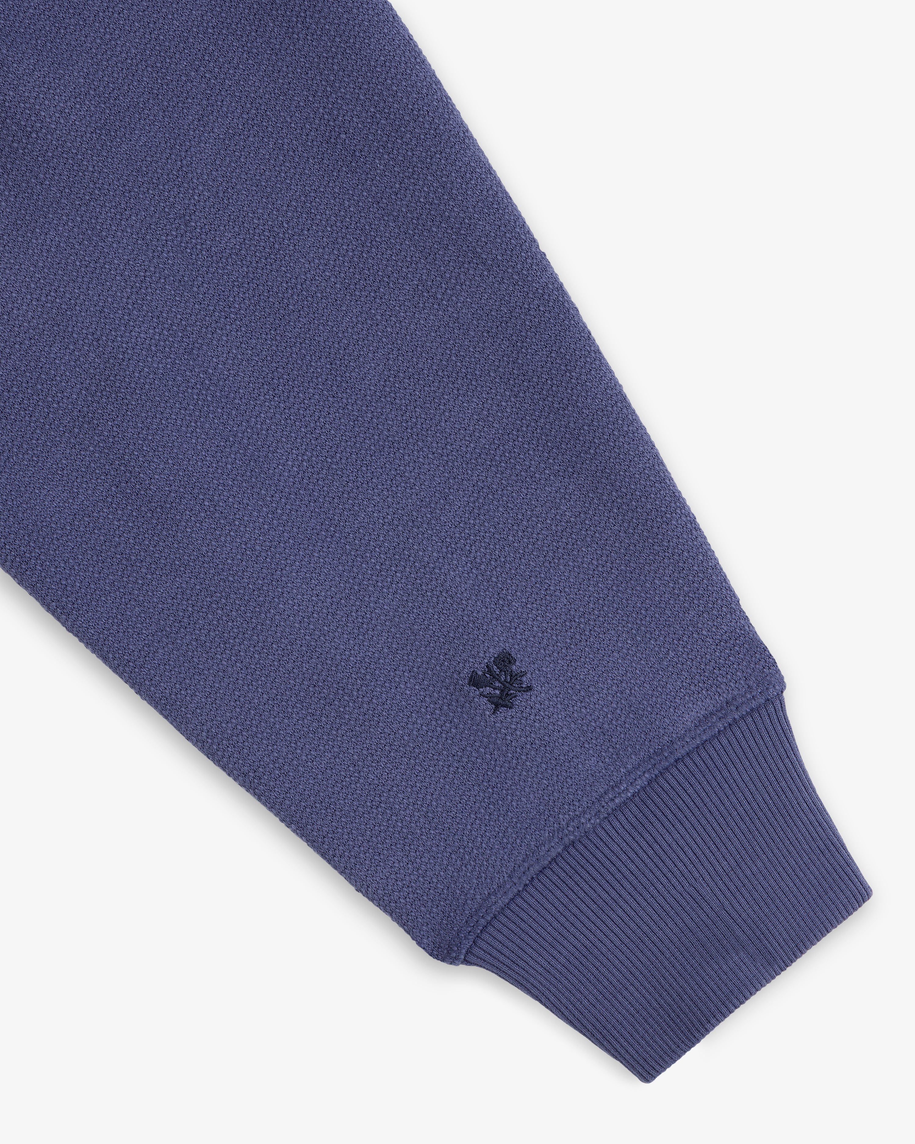 A close-up of the Stone Washed Marina Hoodie’s blue sleeve with ribbed cuff and a black logo near the wrist.