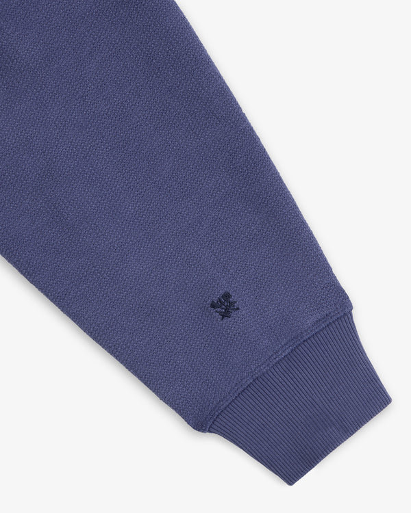 A close-up of the Stone Washed Marina Hoodie’s blue sleeve with ribbed cuff and a black logo near the wrist.