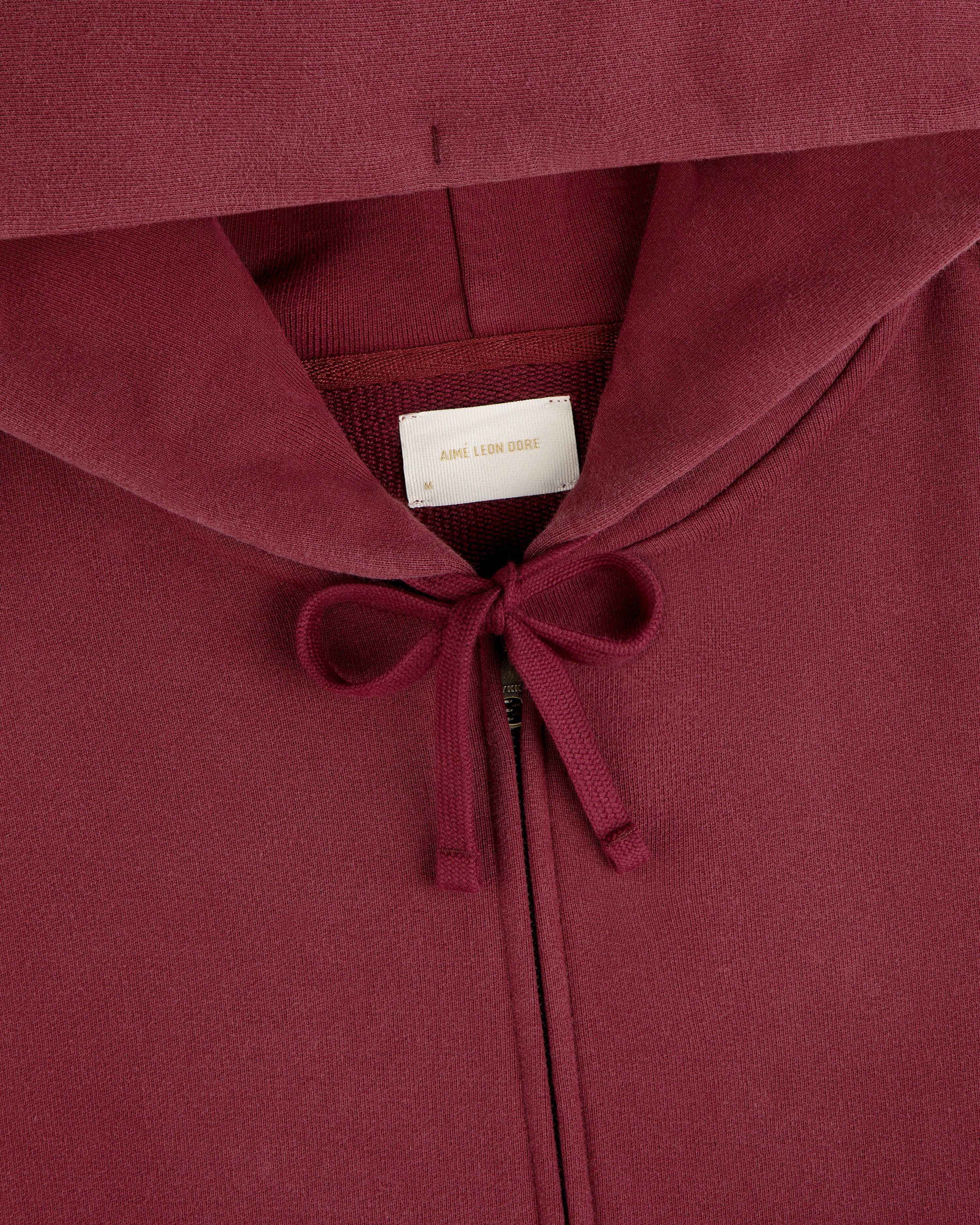 Washed Full Zip Hoodie in maroon with a drawstring hood and a brand label at the neck.