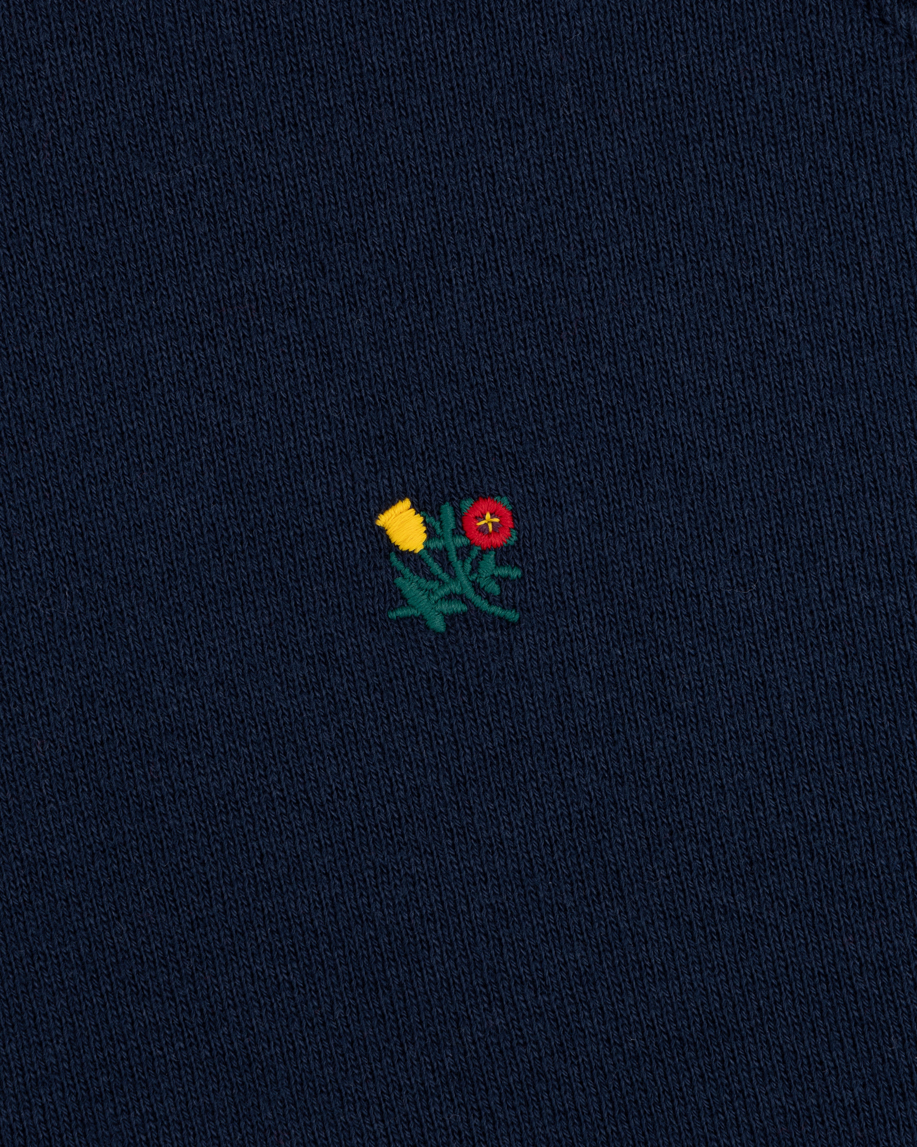 Colorblock Crest Snap Hoodie in dark blue fabric with an embroidered yellow and red flower emblem on green stems.