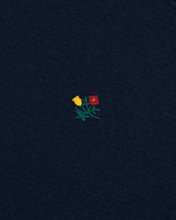 Colorblock Crest Snap Hoodie in dark blue fabric with an embroidered yellow and red flower emblem on green stems.