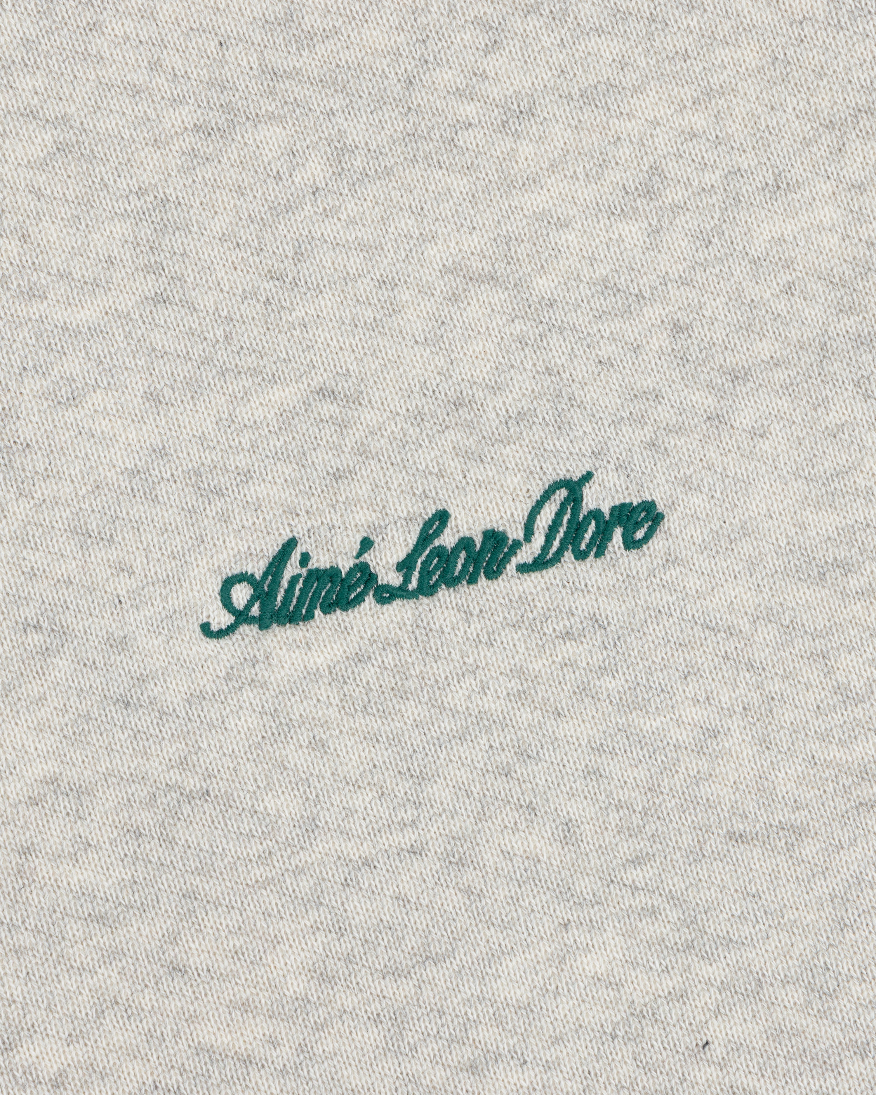 Dark green cursive Aimé Leon Dore embroidery on the grey heather fabric of a Script Full Zip Hoodie.