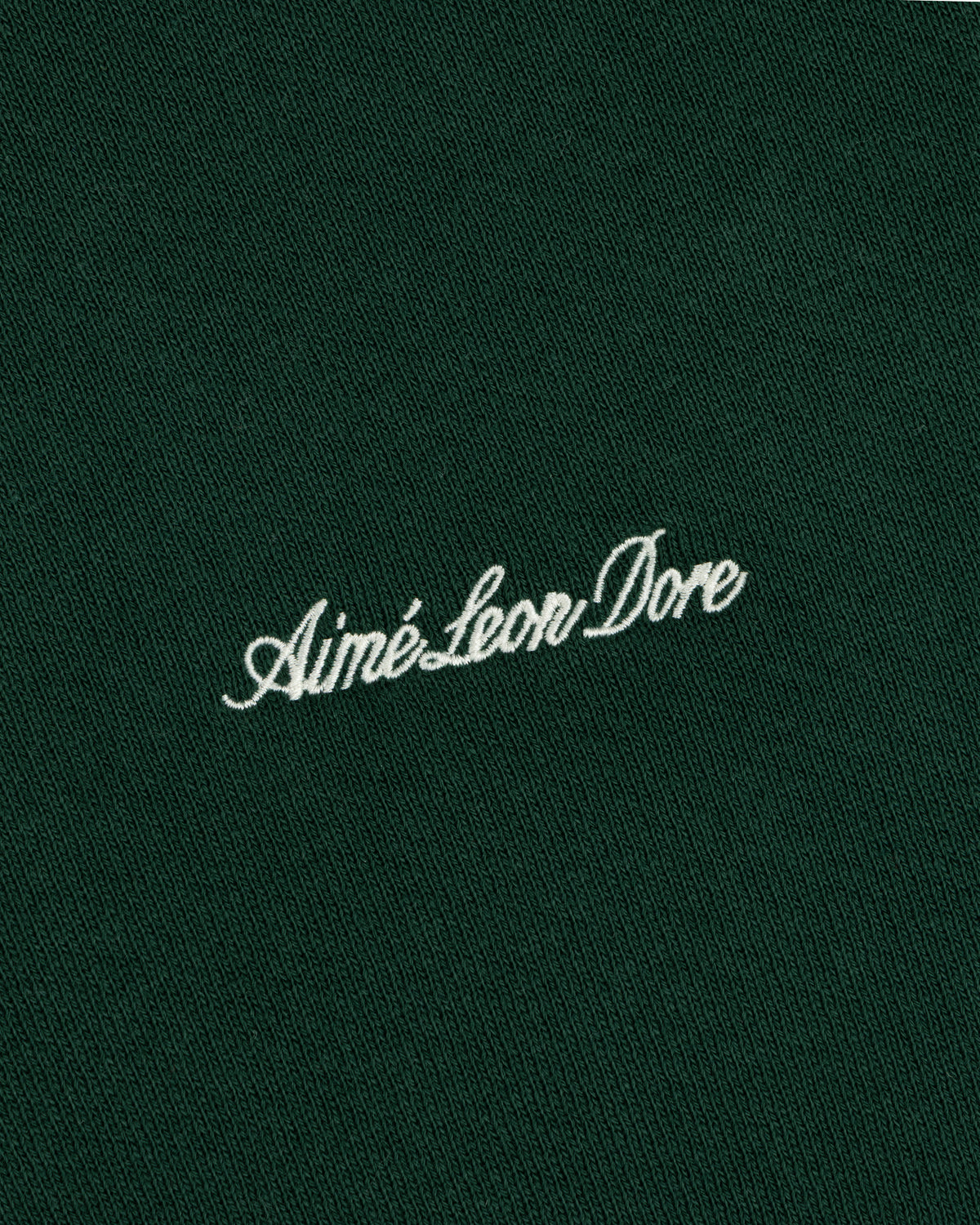 White embroidered Script Full Zip Hoodie logo on a dark green fabric background.