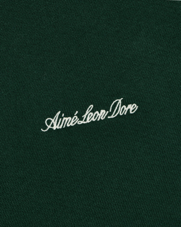 White embroidered Script Full Zip Hoodie logo on a dark green fabric background.