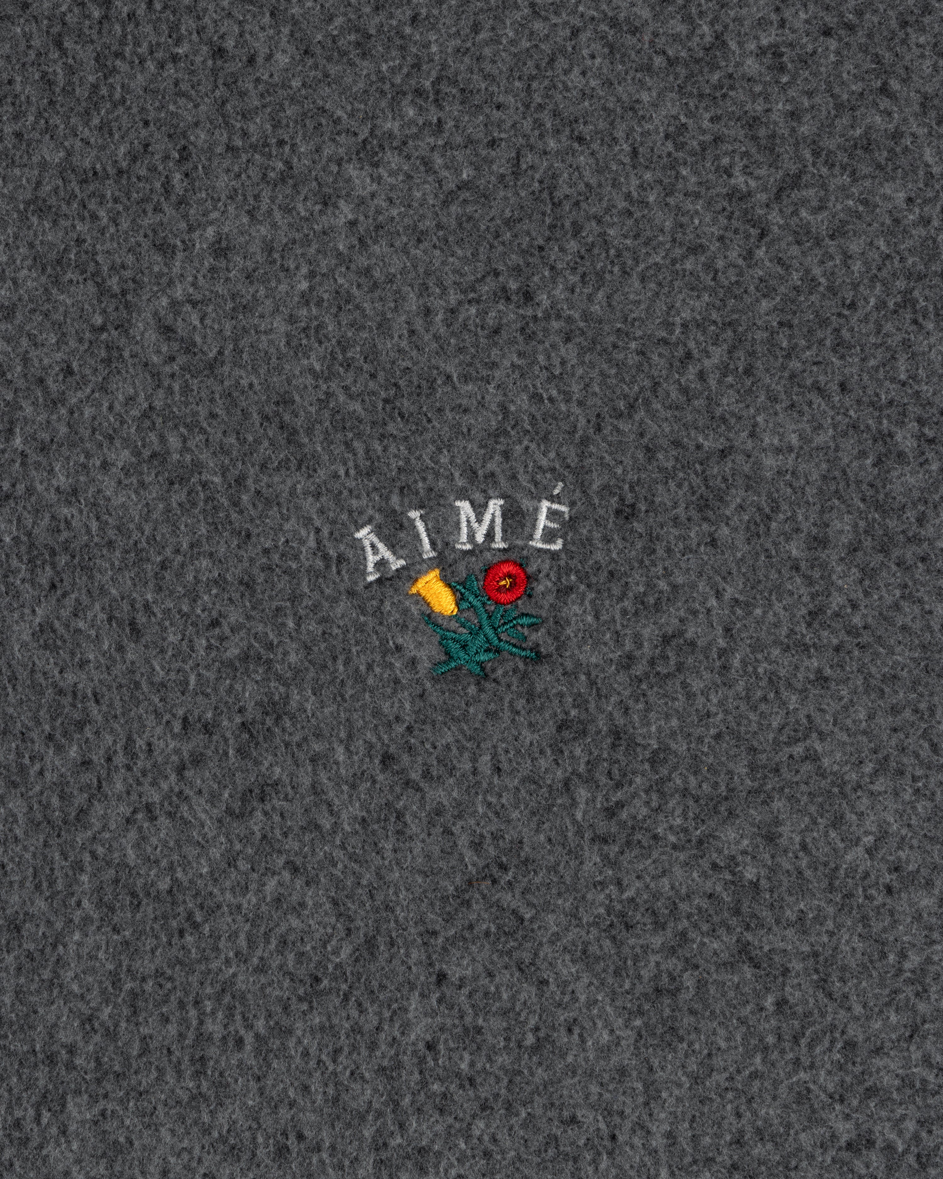 Gray fleece zip hoodie with AIMÉ embroidered above a yellow-red flower with green stems and leaves.
