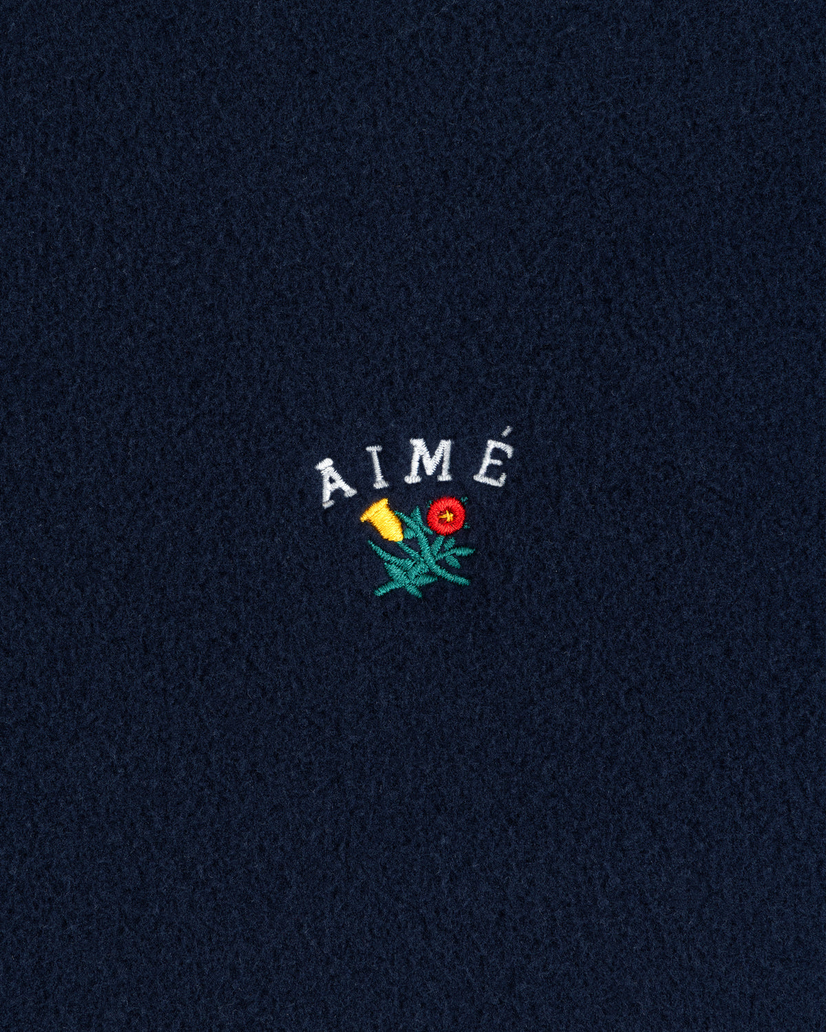 Navy Crest Fleece Full-Zip Hoodie with AIMÉ text and a small yellow-red embroidered flower with green leaves.