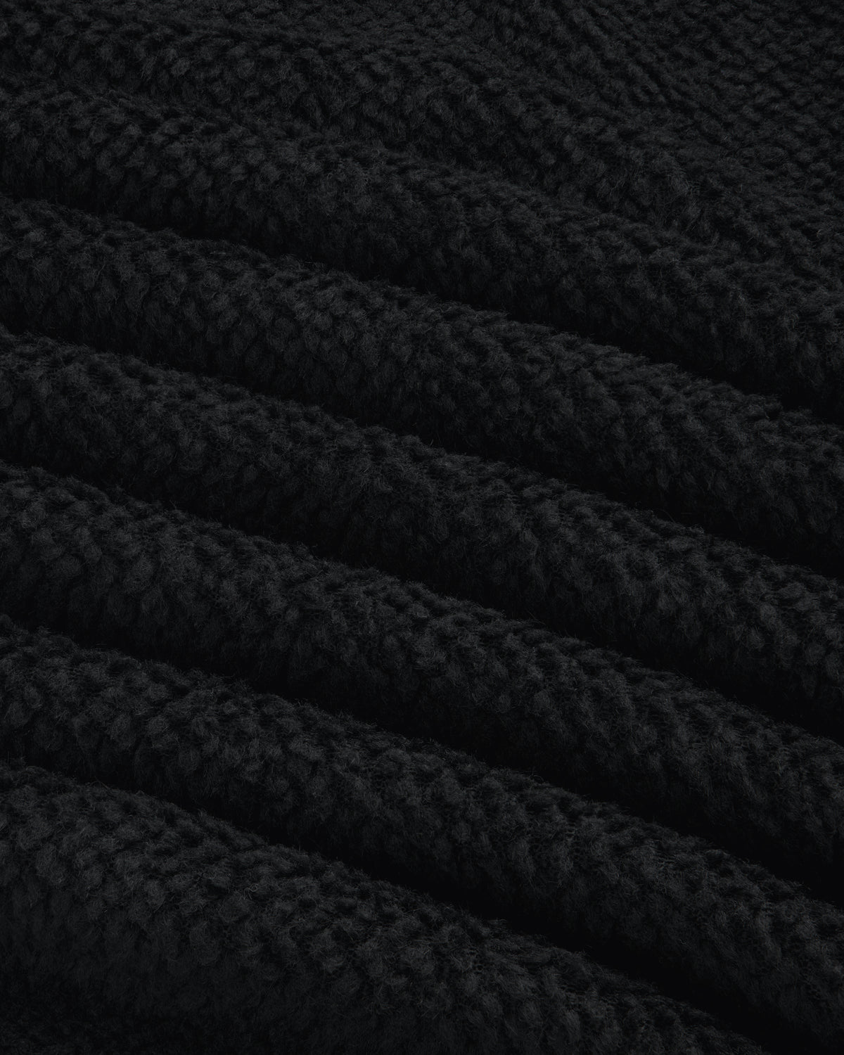 Close-up of black textured fleece fabric with diagonal folds on a Fleece Performance Hoodie.