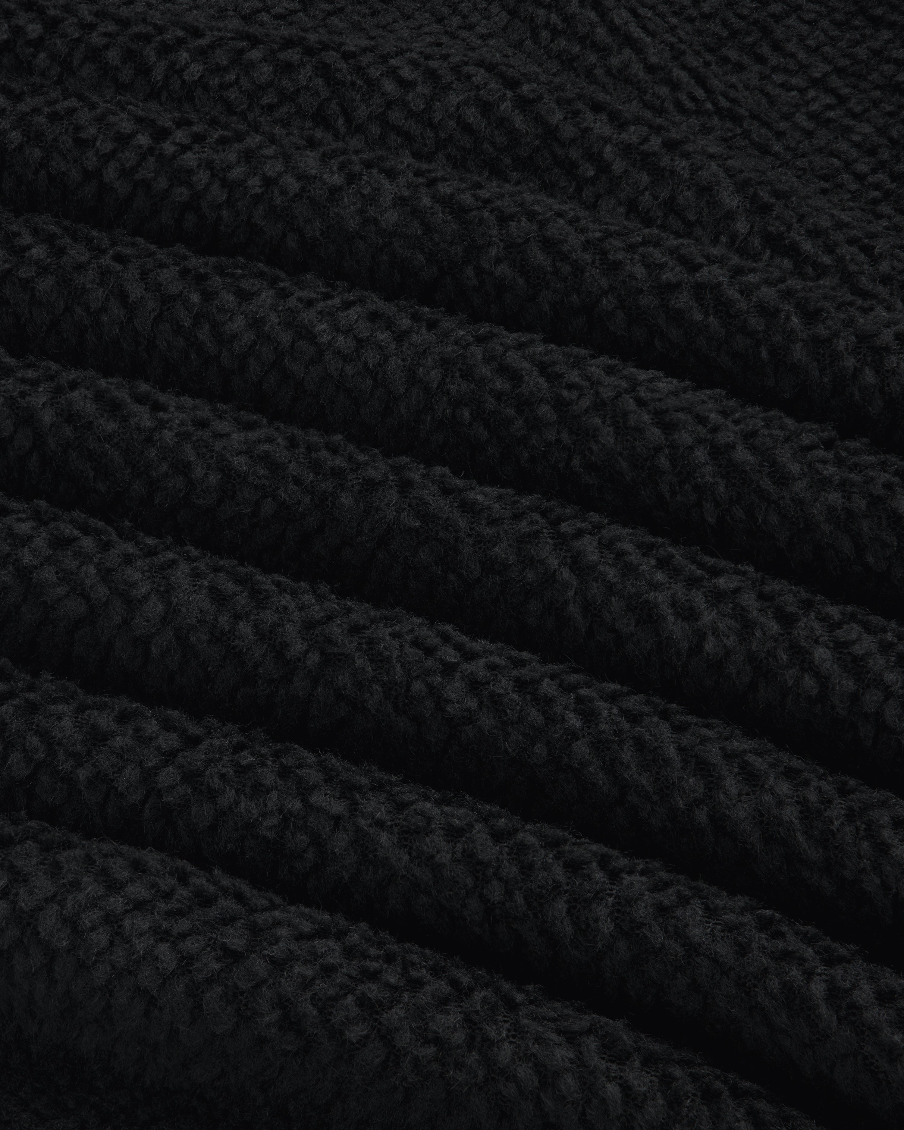 Close-up of black textured fleece fabric with diagonal folds on a Fleece Performance Hoodie.