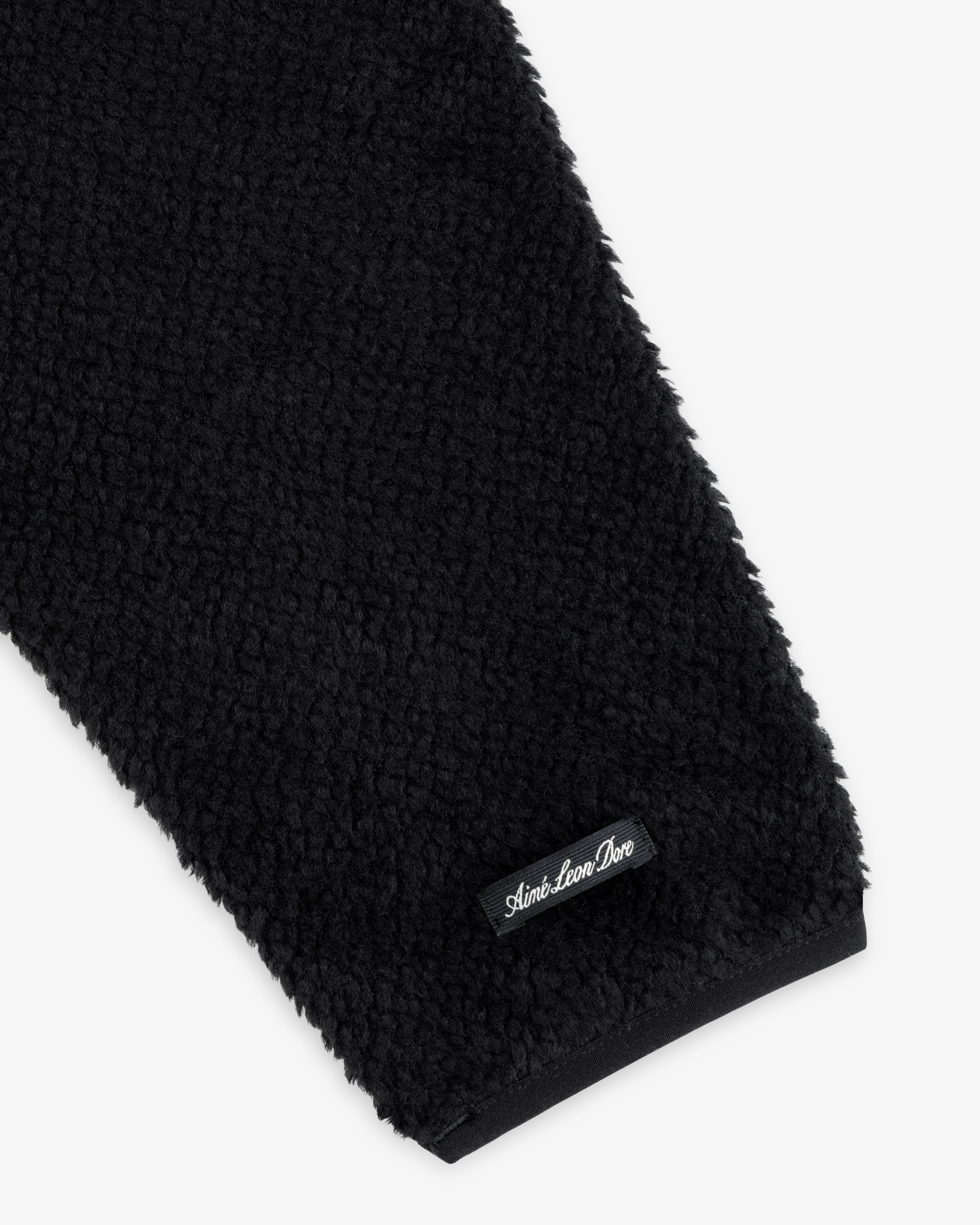 Close-up of a black textured Fleece Performance Hoodie sleeve with a small black brand label at the cuff.