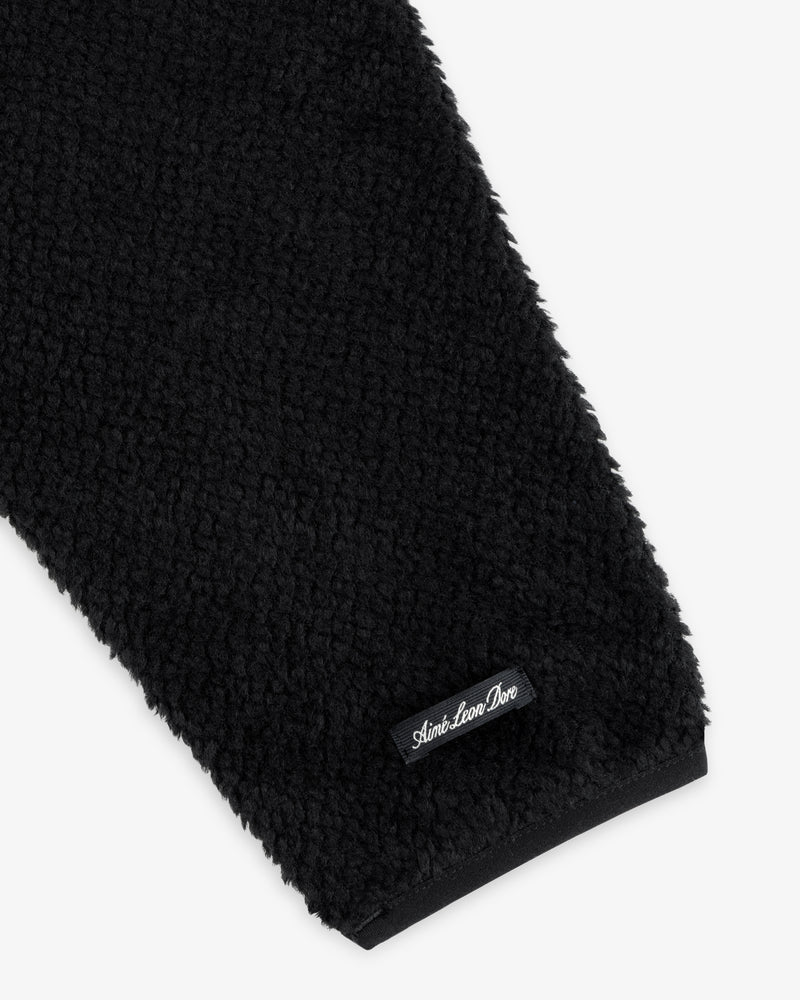 Close-up of a black textured Fleece Performance Hoodie sleeve with a small black brand label at the cuff.