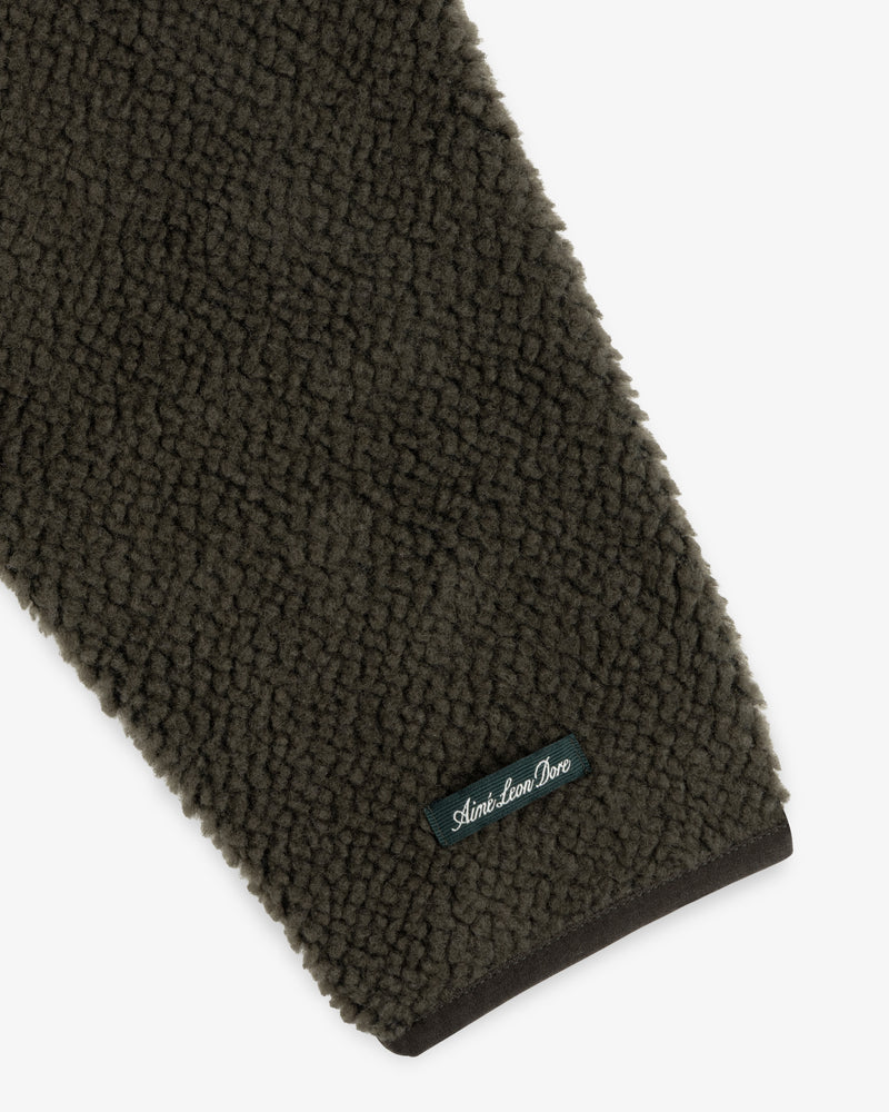 Olive green textured sleeve of a Fleece Performance Hoodie with a small branded patch near the cuff.