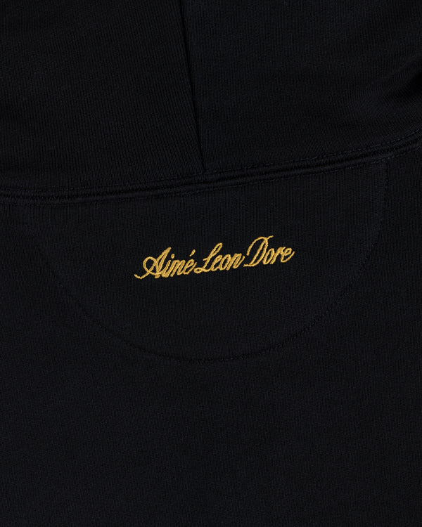 Black fabric of the ALD / Olympiacos F.C. Full Zip Hoodie with Aimé Leon Dore embroidered in gold script.