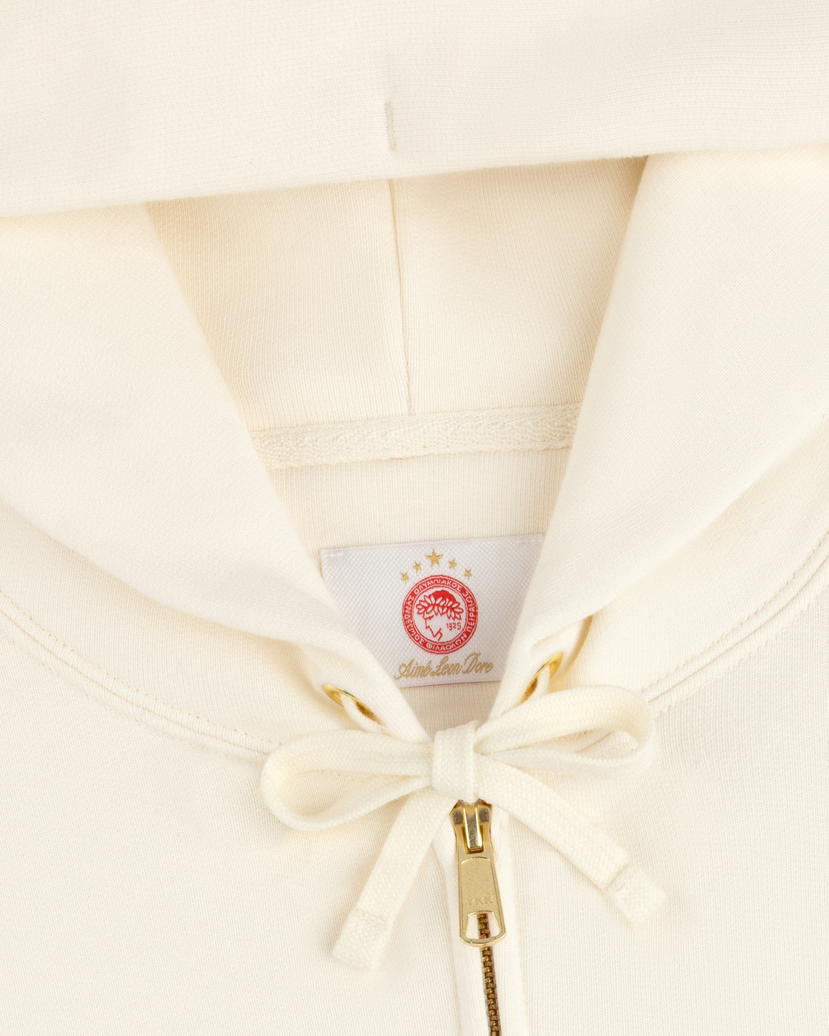 Off-white ALD / Olympiacos F.C. Full Zip Hoodie with a drawstring hood and a red sports logo patch at the neck.