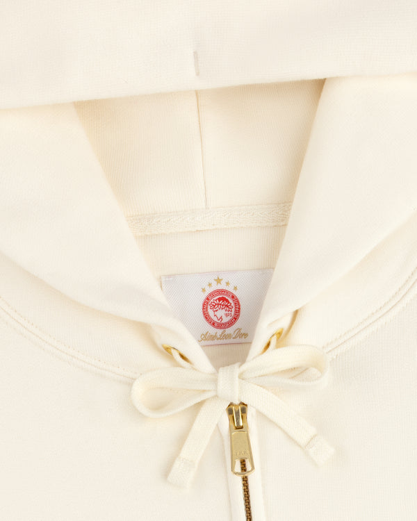 Off-white ALD / Olympiacos F.C. Full Zip Hoodie with a drawstring hood and a red sports logo patch at the neck.