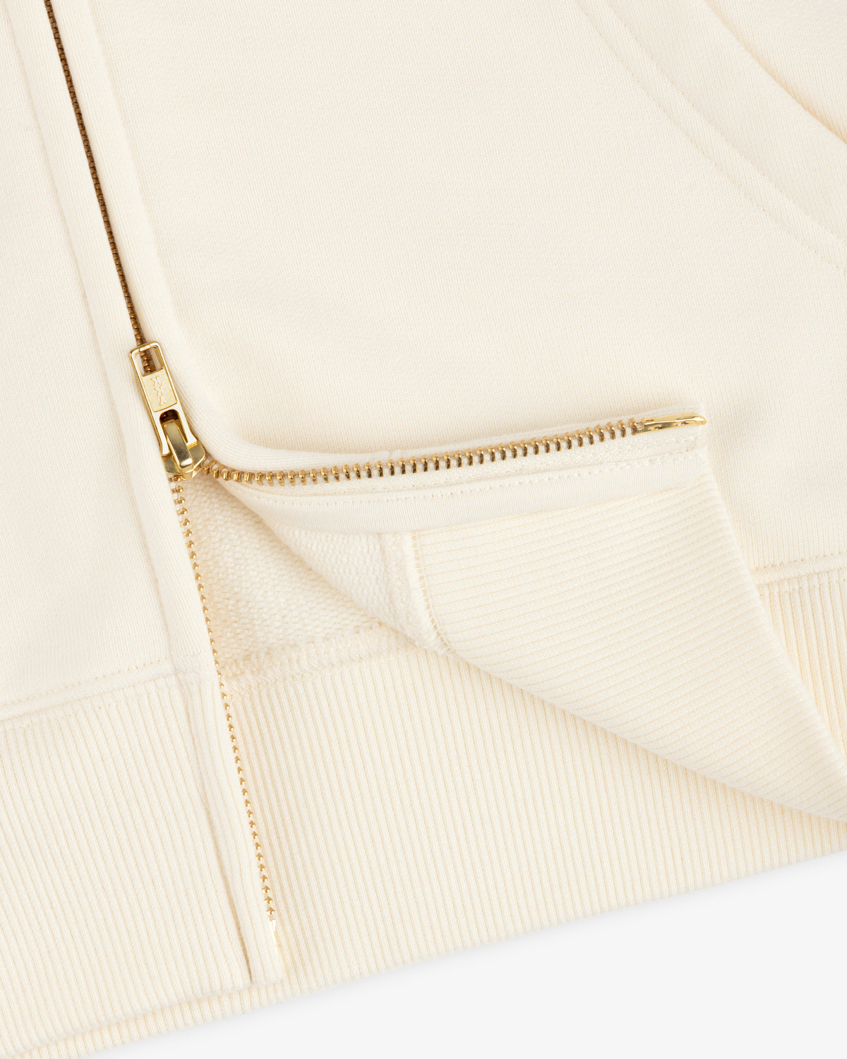 Close-up of the cream-colored ALD / Olympiacos F.C. Full Zip Hoodie, featuring a gold-toned metal zipper.