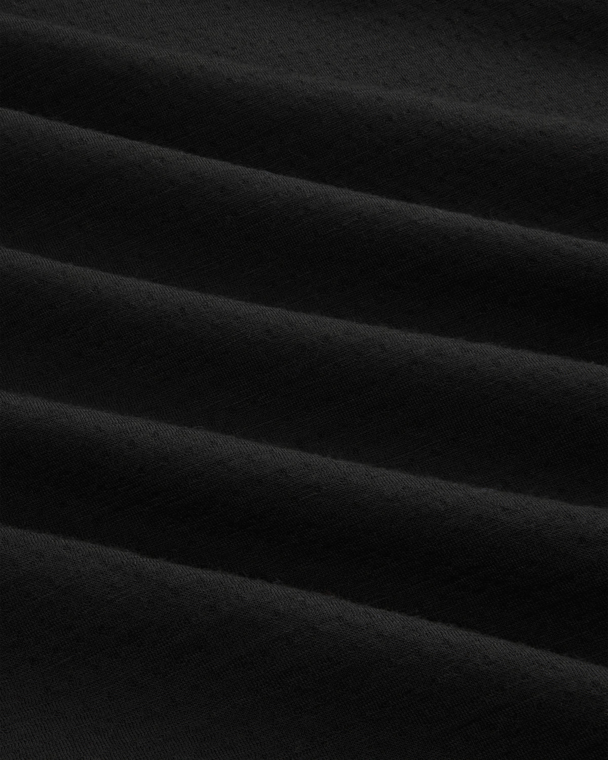 Close-up of ALD / The North Face DOTKNIT™ Wool Quarter Zip’s soft black fabric with gentle, rippled folds.