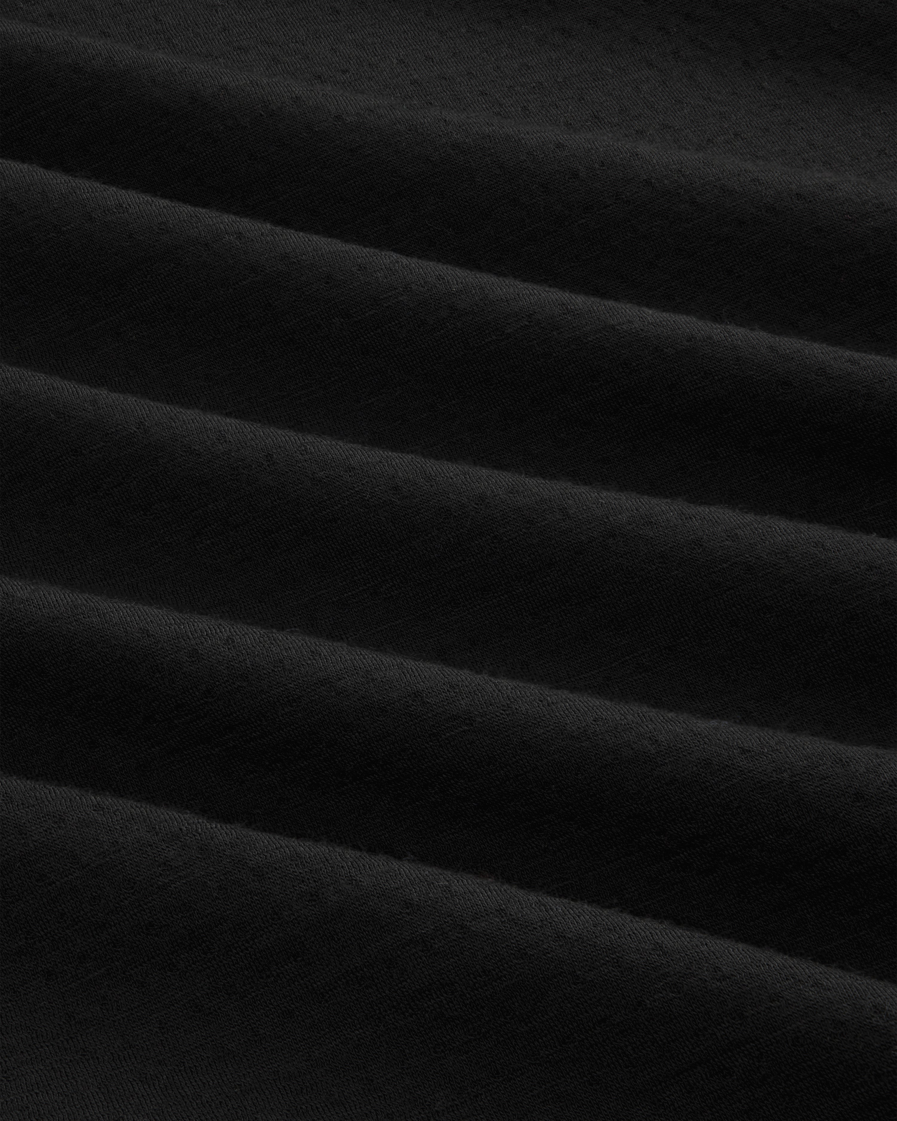 Close-up of ALD / The North Face DOTKNIT™ Wool Quarter Zip’s soft black fabric with gentle, rippled folds.