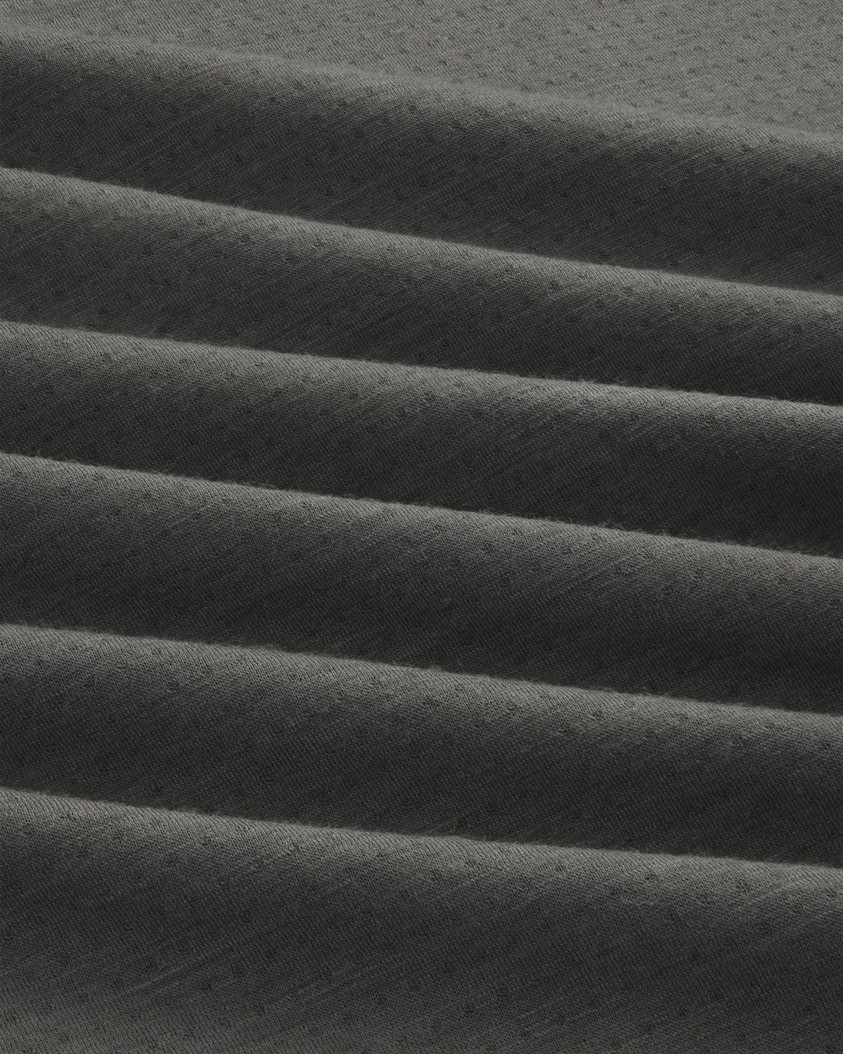 Close-up of ALD/The North Face DOTKNIT™ Wool Quarter Zip in dark grey with ribbed, diagonally folded textured fabric.