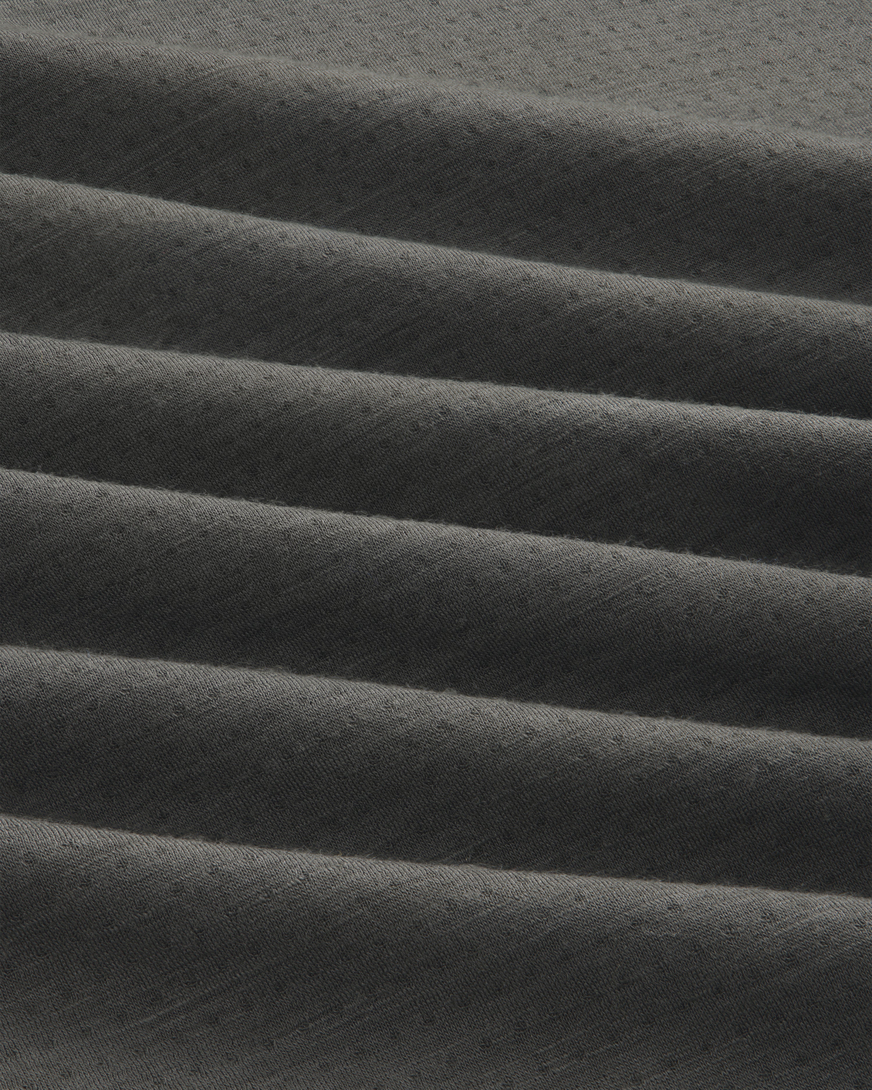 Close-up of ALD/The North Face DOTKNIT™ Wool Quarter Zip in dark grey with ribbed, diagonally folded textured fabric.