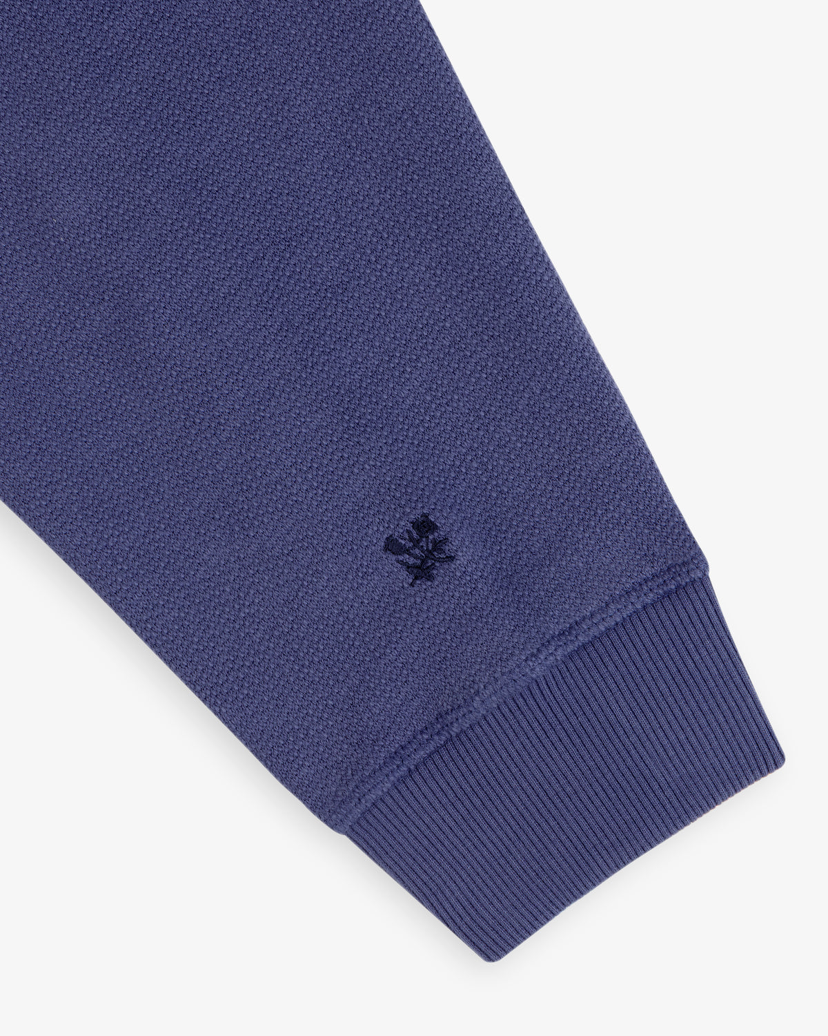 Close-up of Stone Washed Marina Crewneck’s blue sleeve, ribbed cuff, and small embroidered logo near the cuff.