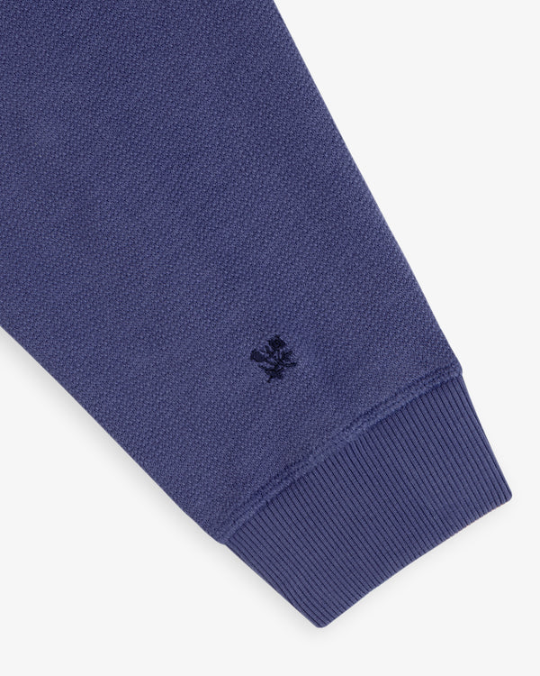 Close-up of Stone Washed Marina Crewneck’s blue sleeve, ribbed cuff, and small embroidered logo near the cuff.