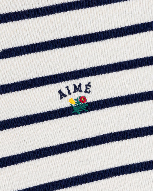 Striped Crest Quarter Zip—white/navy stripes, “AIMÉ” text, plus small yellow and red flower embroidery underneath.