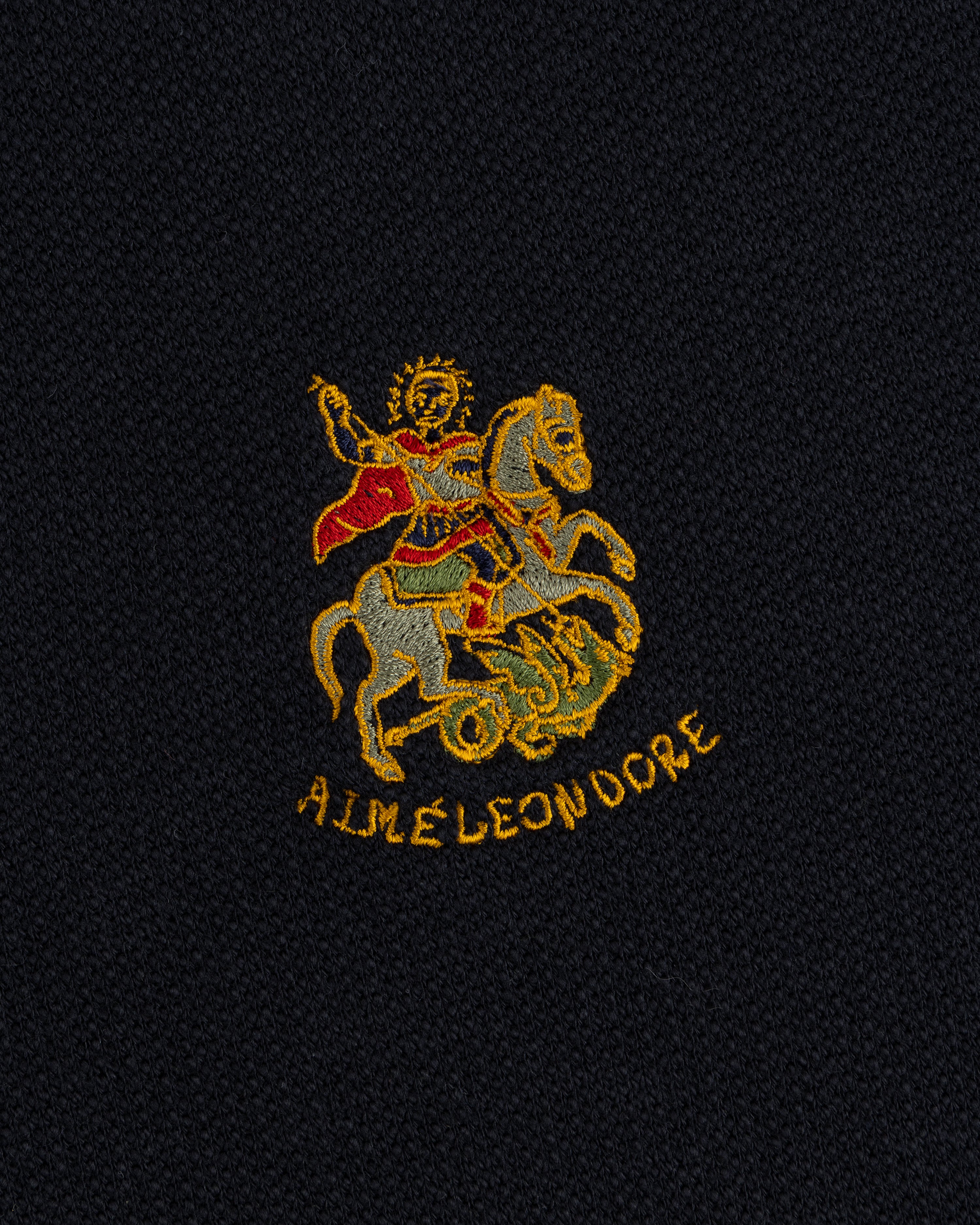 Saint George slays a dragon, AIME LEON DORE text below, on the Saint George Track Jacket’s dark fabric.