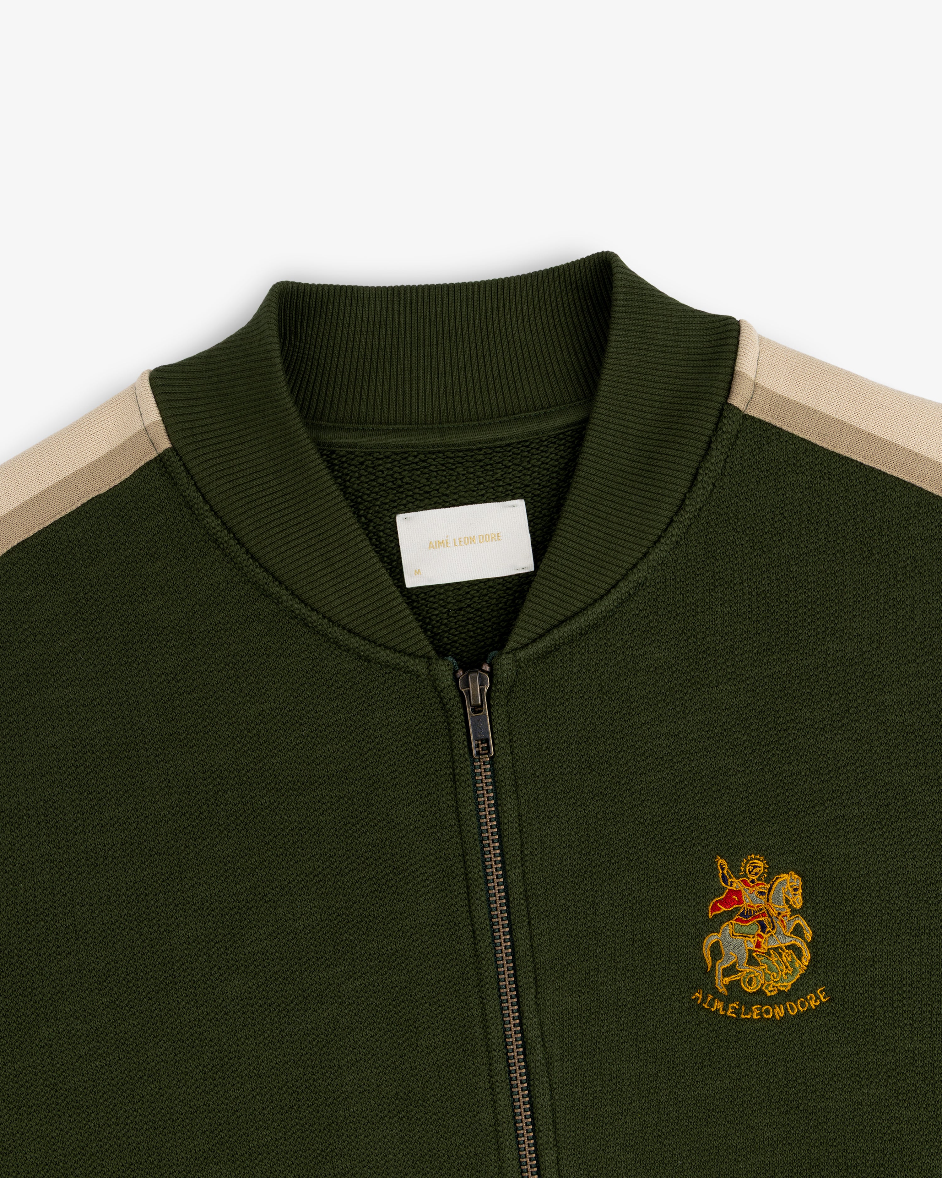 Saint George Track Jacket: Olive green zip-up with beige shoulder stripes and an embroidered chest crest.