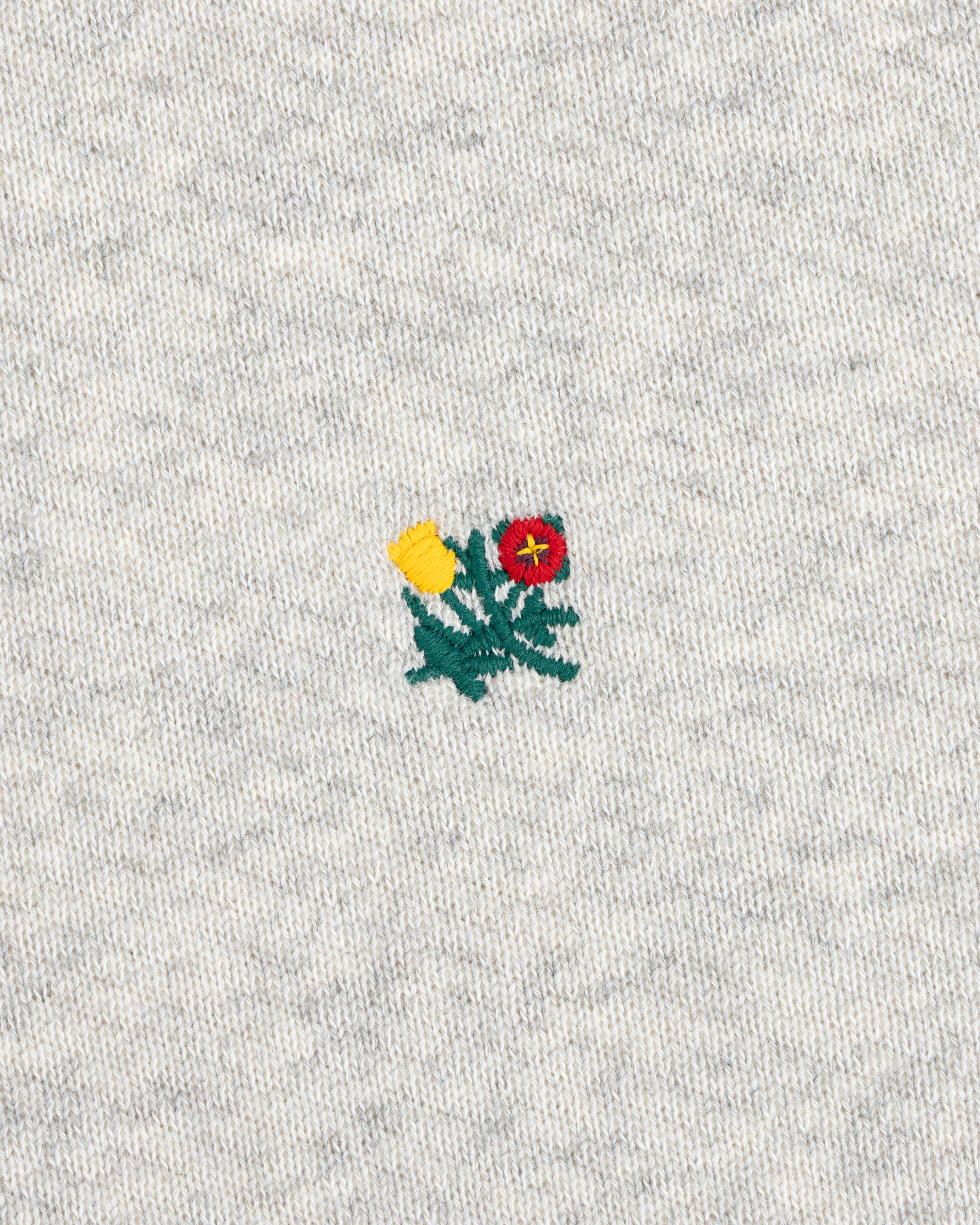 Crest Crewneck Sweatshirt with a small yellow and red flower patch embroidered on gray heathered fabric.