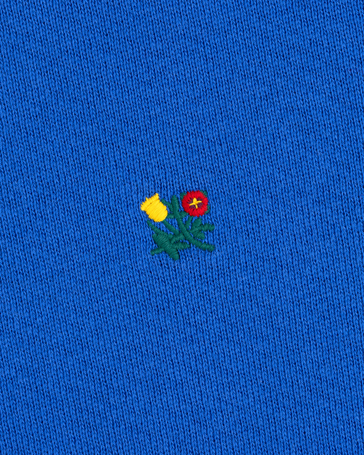 Crest Crewneck Sweatshirt in bright blue with a small embroidered yellow thistle and red flower.