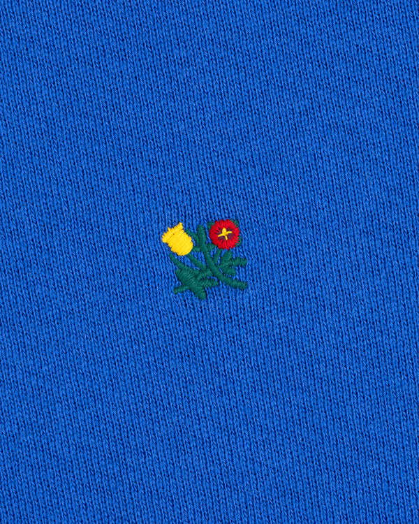 Crest Crewneck Sweatshirt in bright blue with a small embroidered yellow thistle and red flower.