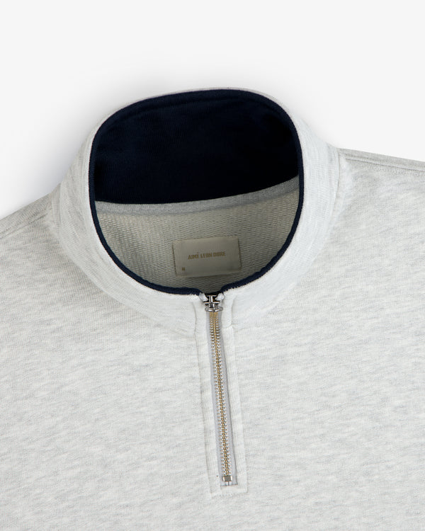 Aimé Souvenir Quarter Zip in light grey with silver zipper and dark collar lining, laid flat on a white background.