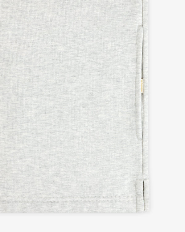 Close-up of the Aimé Souvenir Quarter Zip’s light grey fabric, side seam, hem, and small beige tag on the edge.