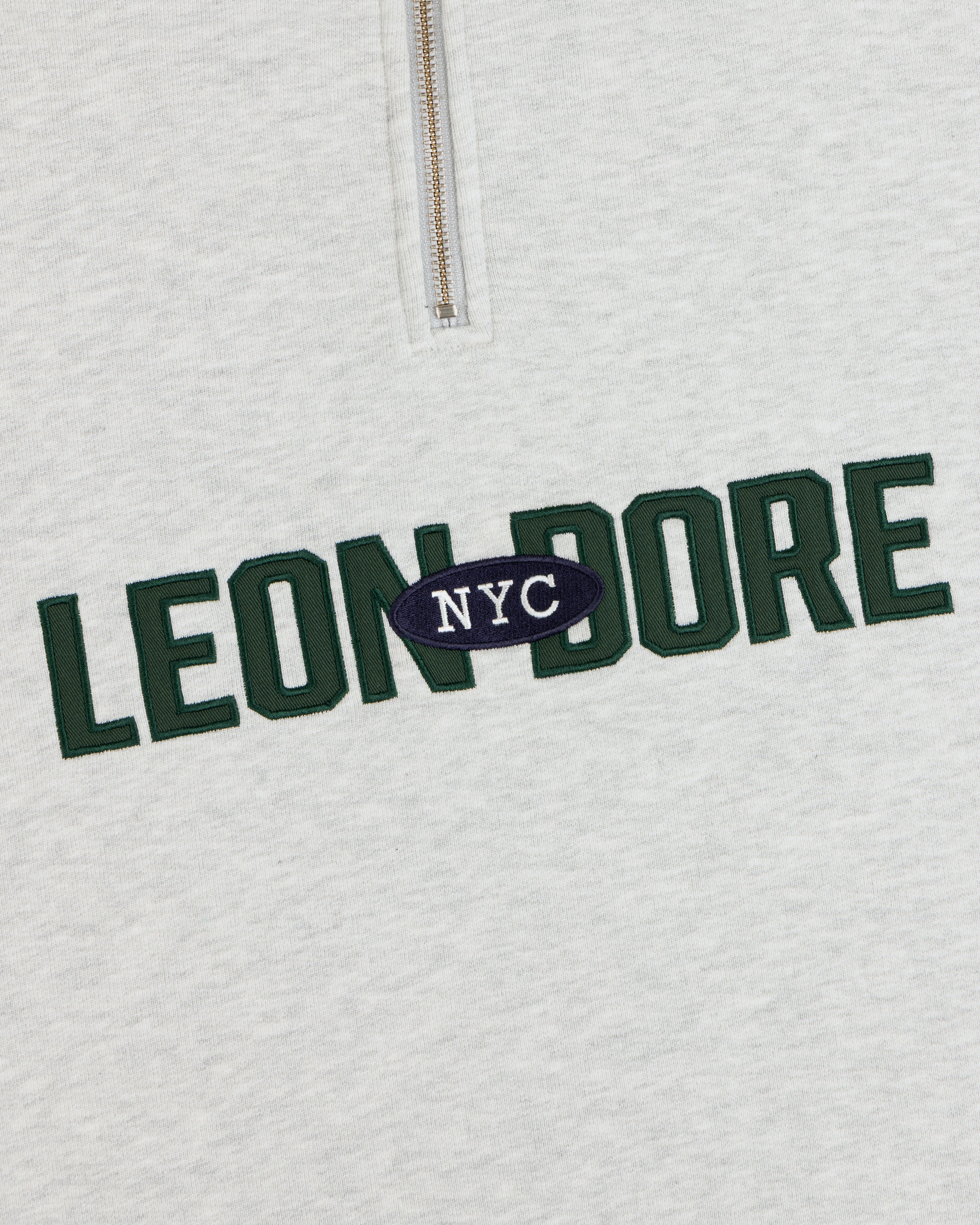 Aimé Souvenir Quarter Zip: cream sweatshirt with green LEON DORE & white NYC on a navy oval in the center.