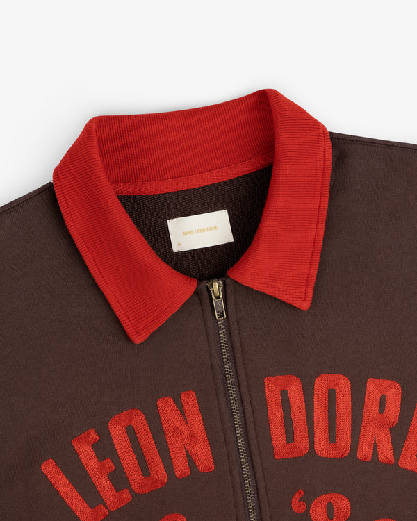 Dark brown Chainstitch ’86 Half Zip Pullover with a red ribbed collar and red embroidered lettering across the chest.