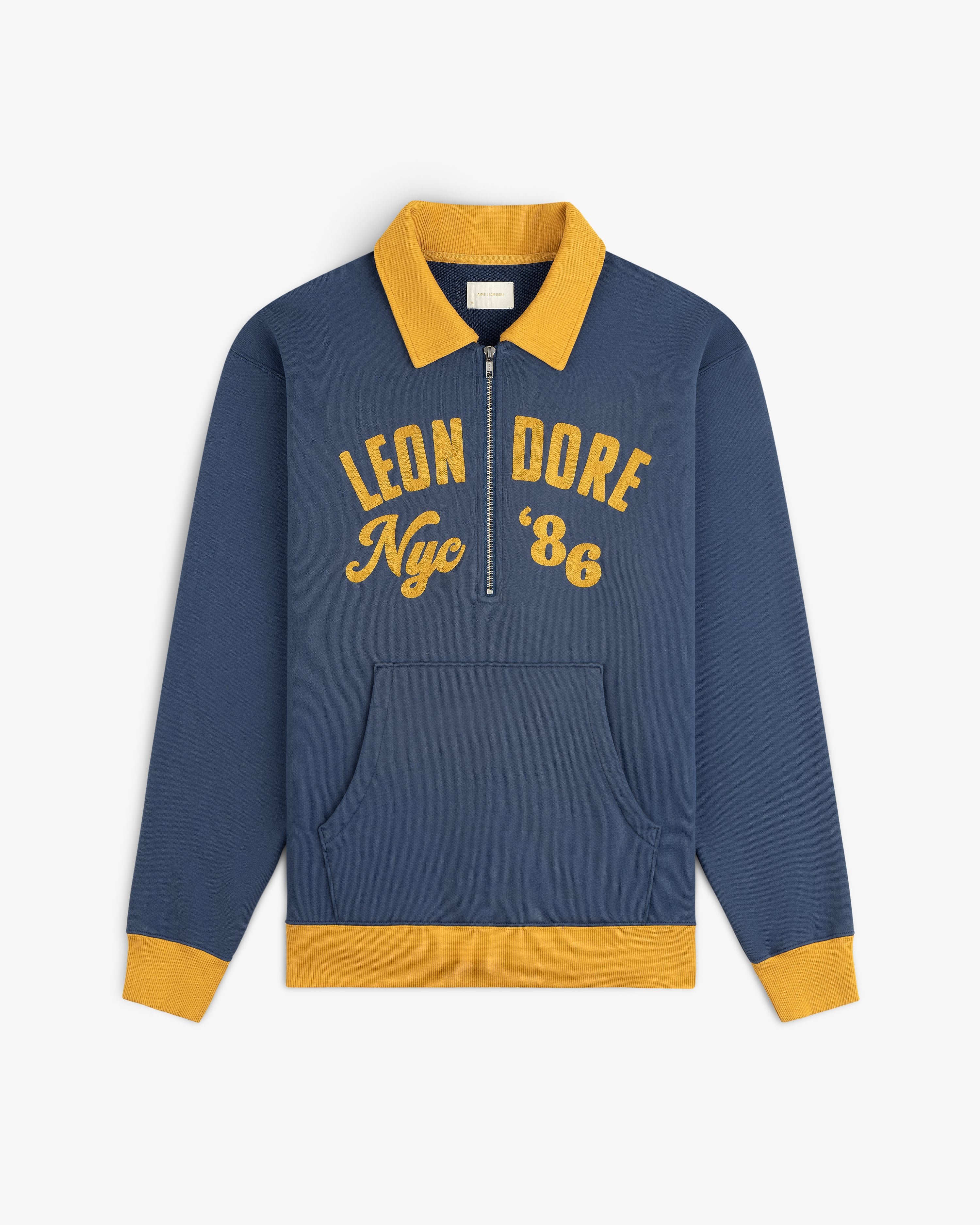 Blue Chainstitch ’86 Half Zip Pullover with a gold collar, cuffs, and hem, featuring LEON DORE Nyc 86 in gold lettering.
