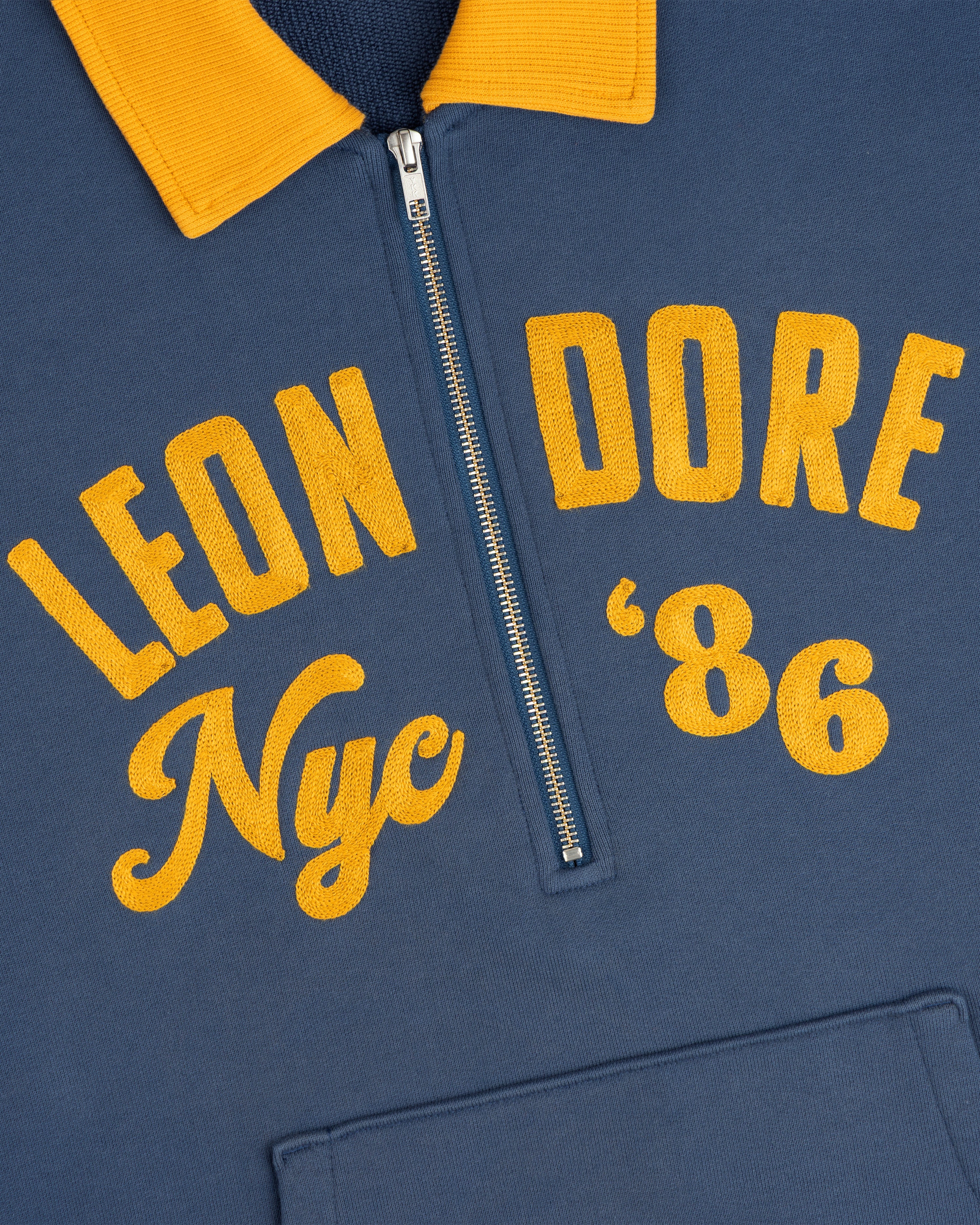 Chainstitch ’86 Half Zip Pullover in blue with a yellow collar and yellow Leon Dore Nyc 86 embroidery.