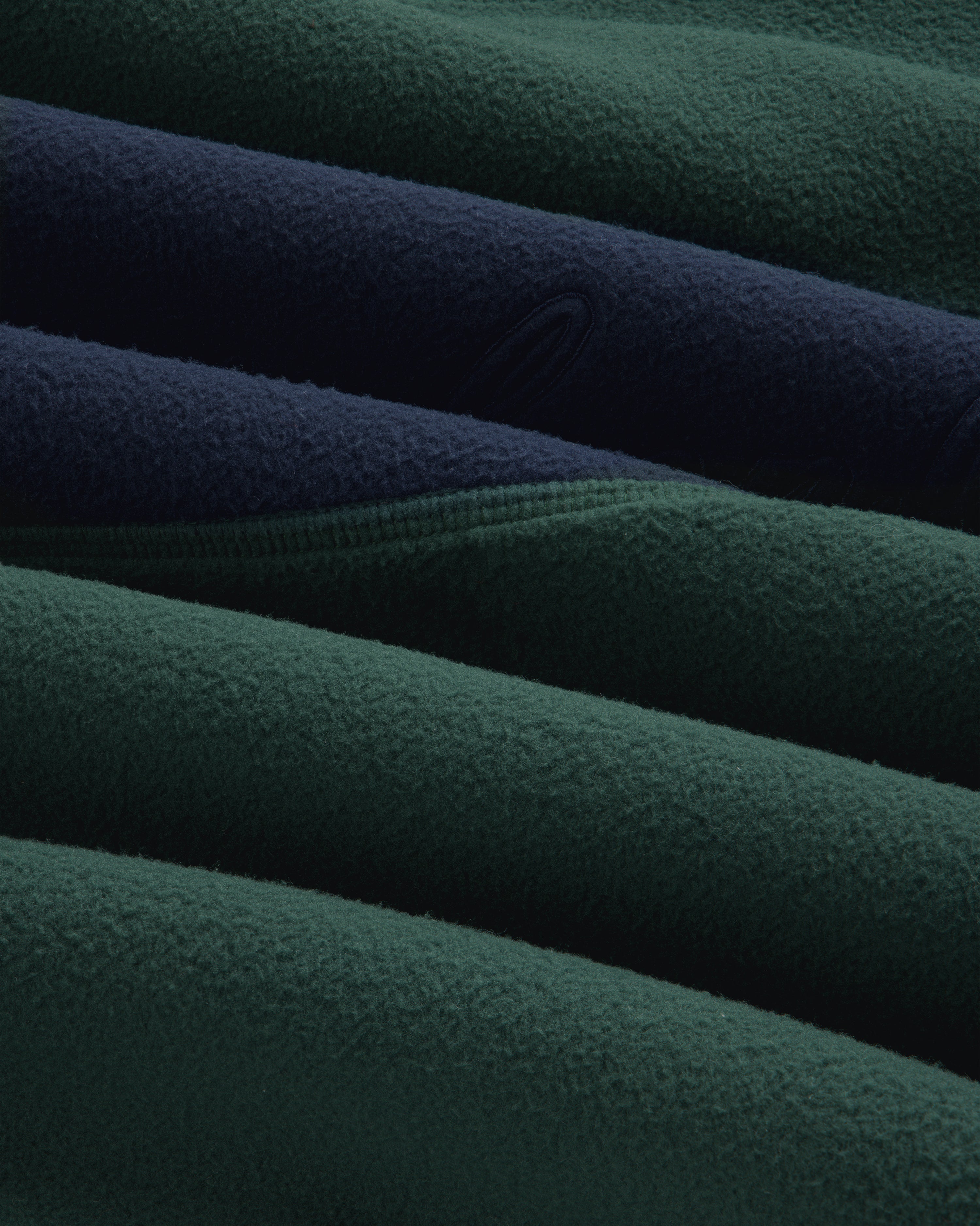 Close-up of a dark green and navy blue Fleece Script Paneled Crewneck Sweatshirt with visible seams.