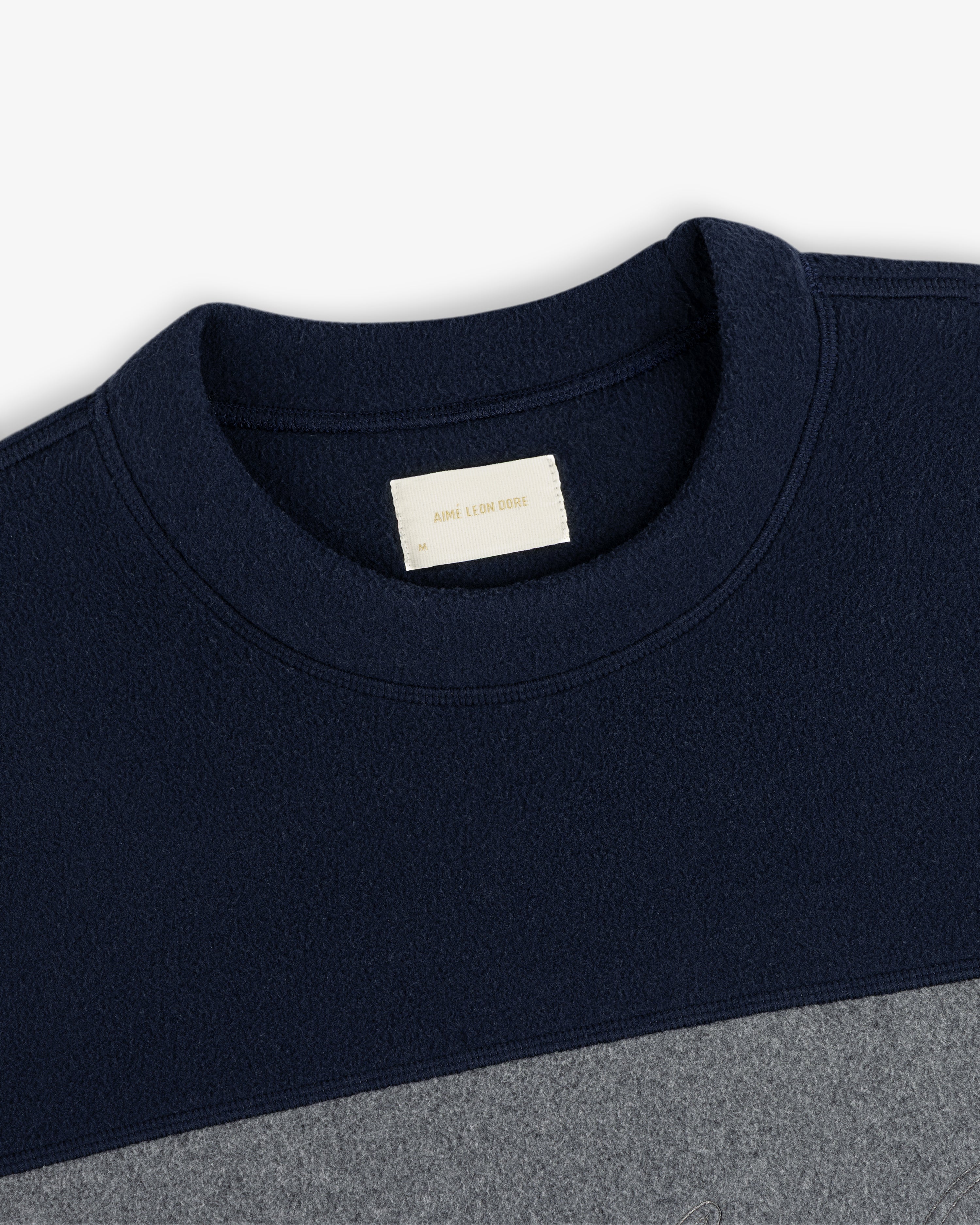 Fleece Script Paneled Crewneck Sweatshirt in navy and grey color-blocked with a brand label at the inner neckline.