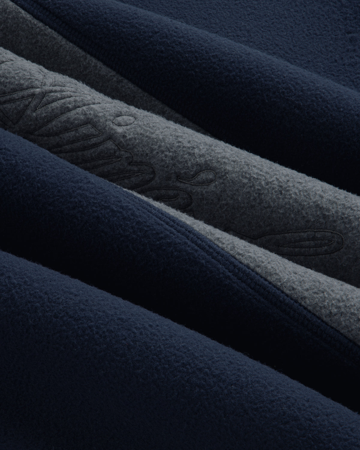 Close-up of a navy and grey Fleece Script Paneled Crewneck Sweatshirt with embroidered script detailing.